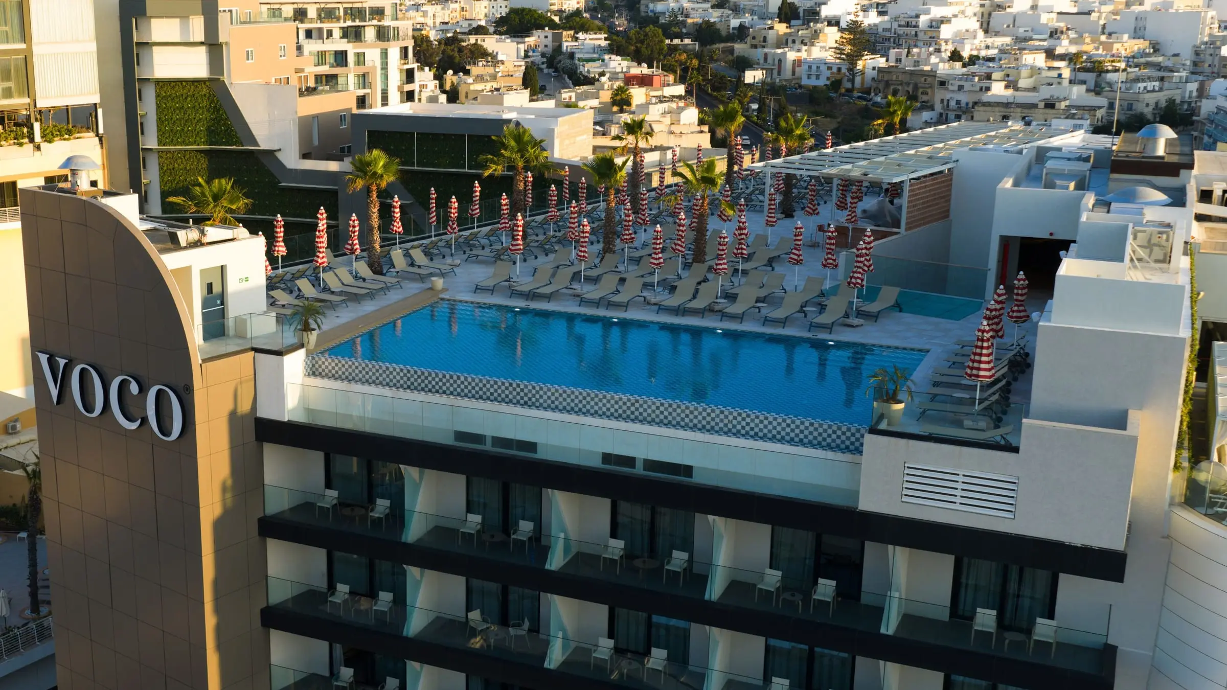 The voco Malta pool deck from above, loungers in rows