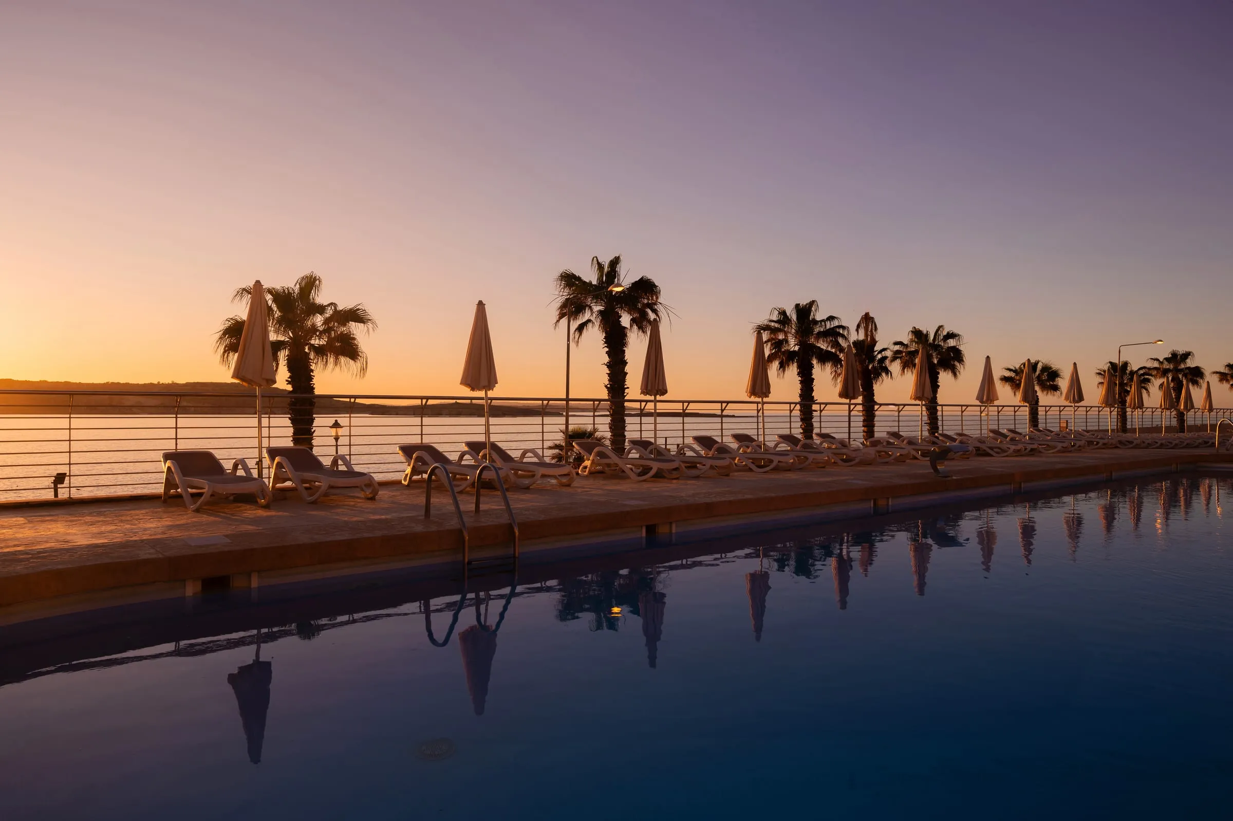 The outdoor pool at DoubleTree by Hilton Malta at sunset, overlooking St Paul’s Bay