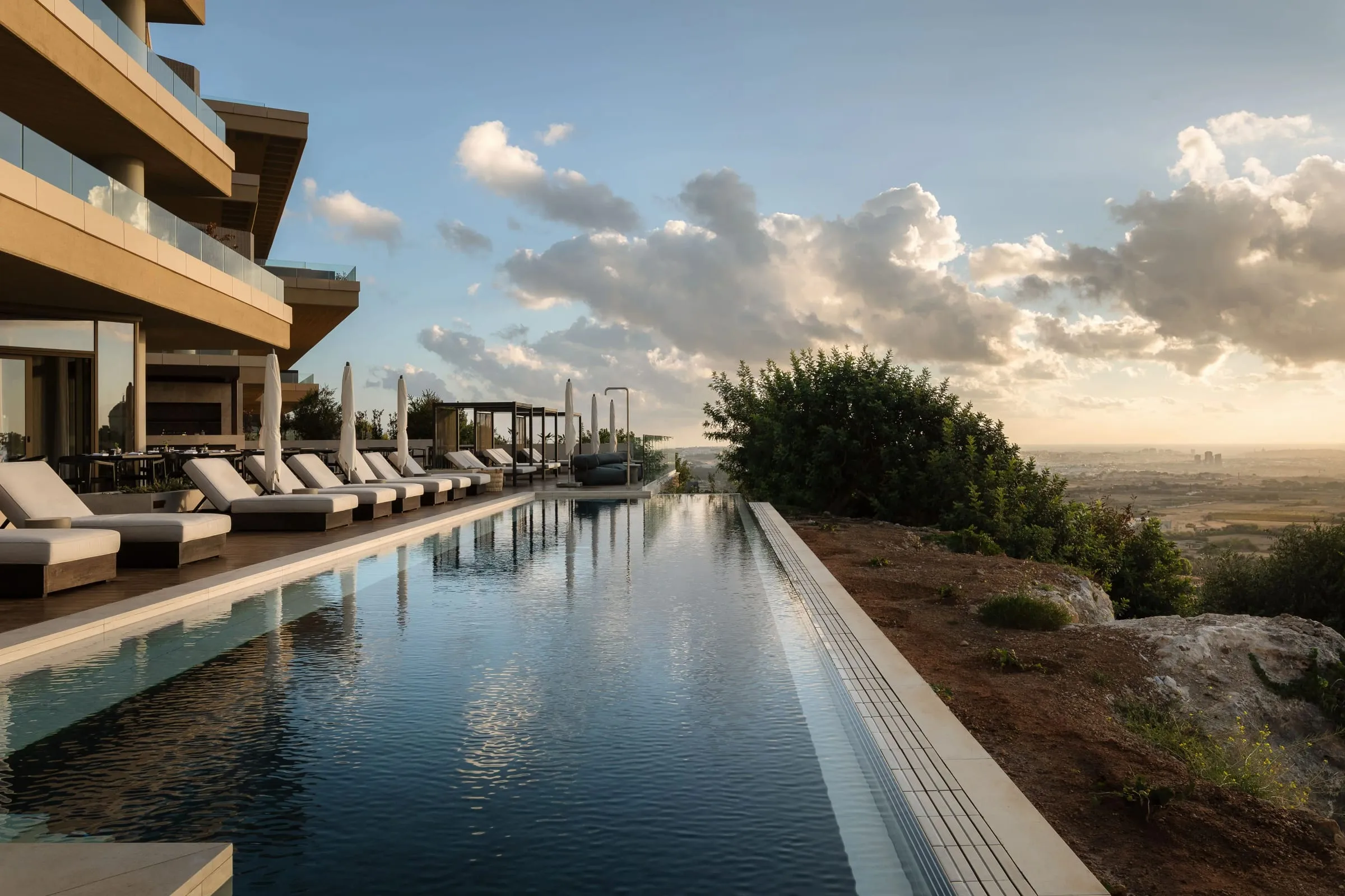 The outdoor infinity pool of the Verdala Wellness Hotel, loungers along its edge and the countryside below