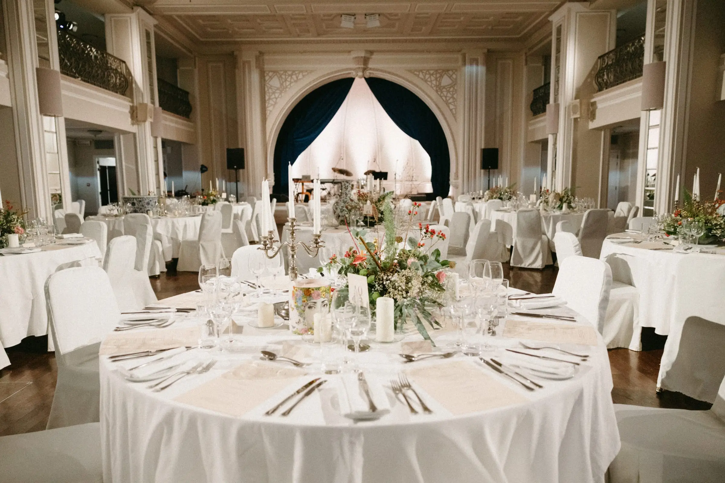 The Grand Ballroom laid with round tables for a dinner, its stage arch behind