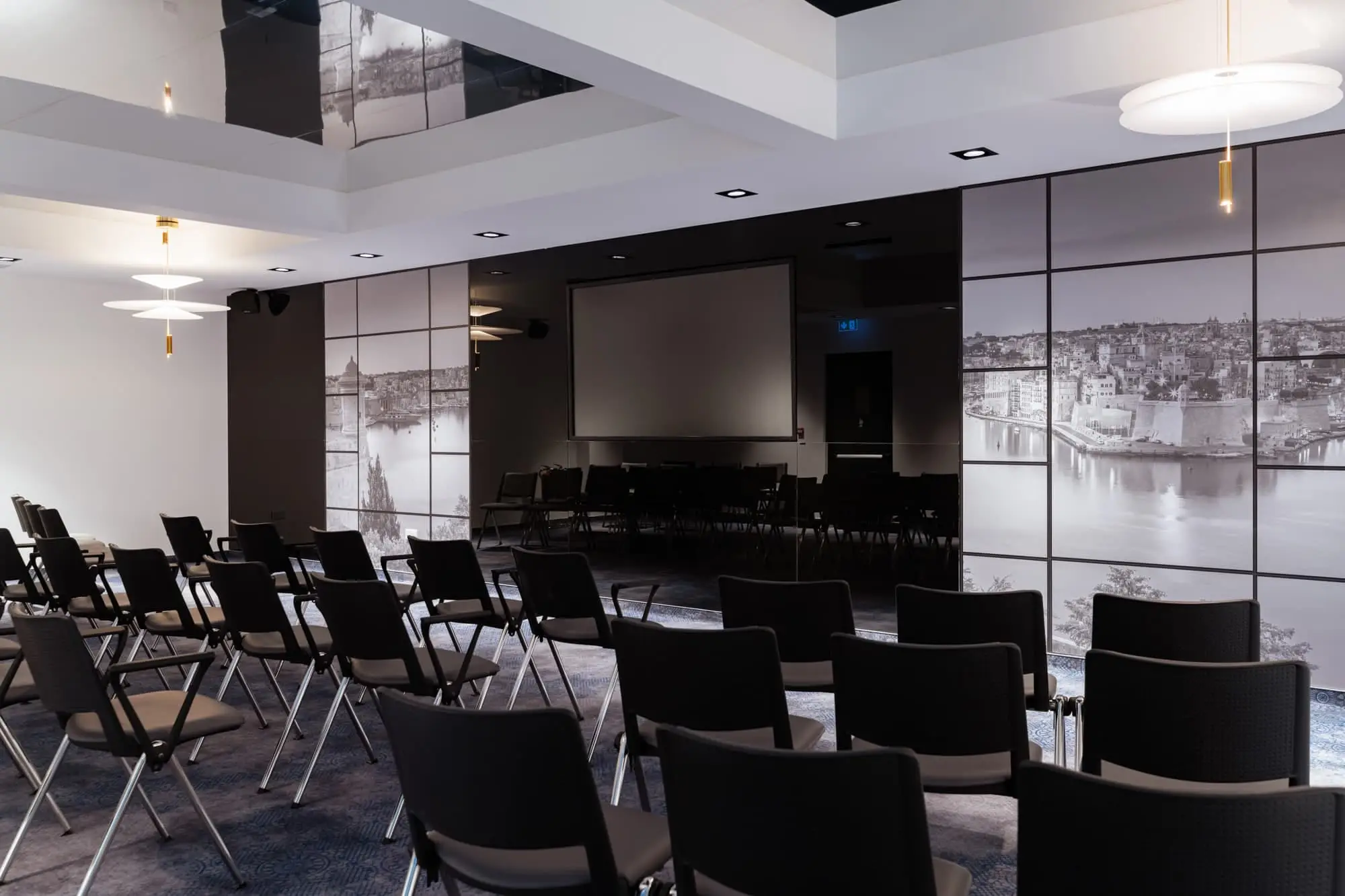 The Ambassador Suite set theatre-style facing a screen, its walls printed with black-and-white harbour views
