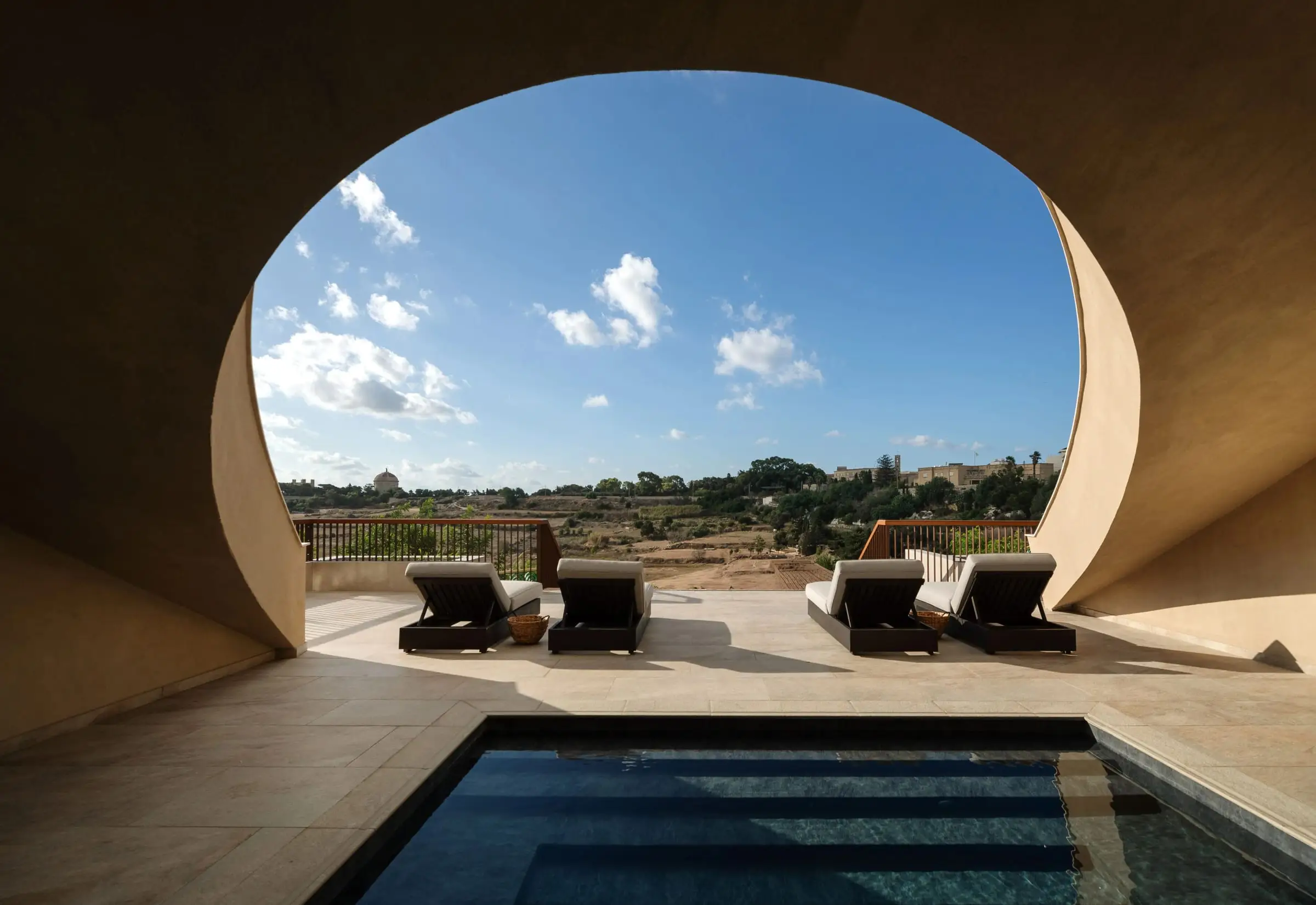 An outdoor jacuzzi under a curved stone arch, the countryside beyond