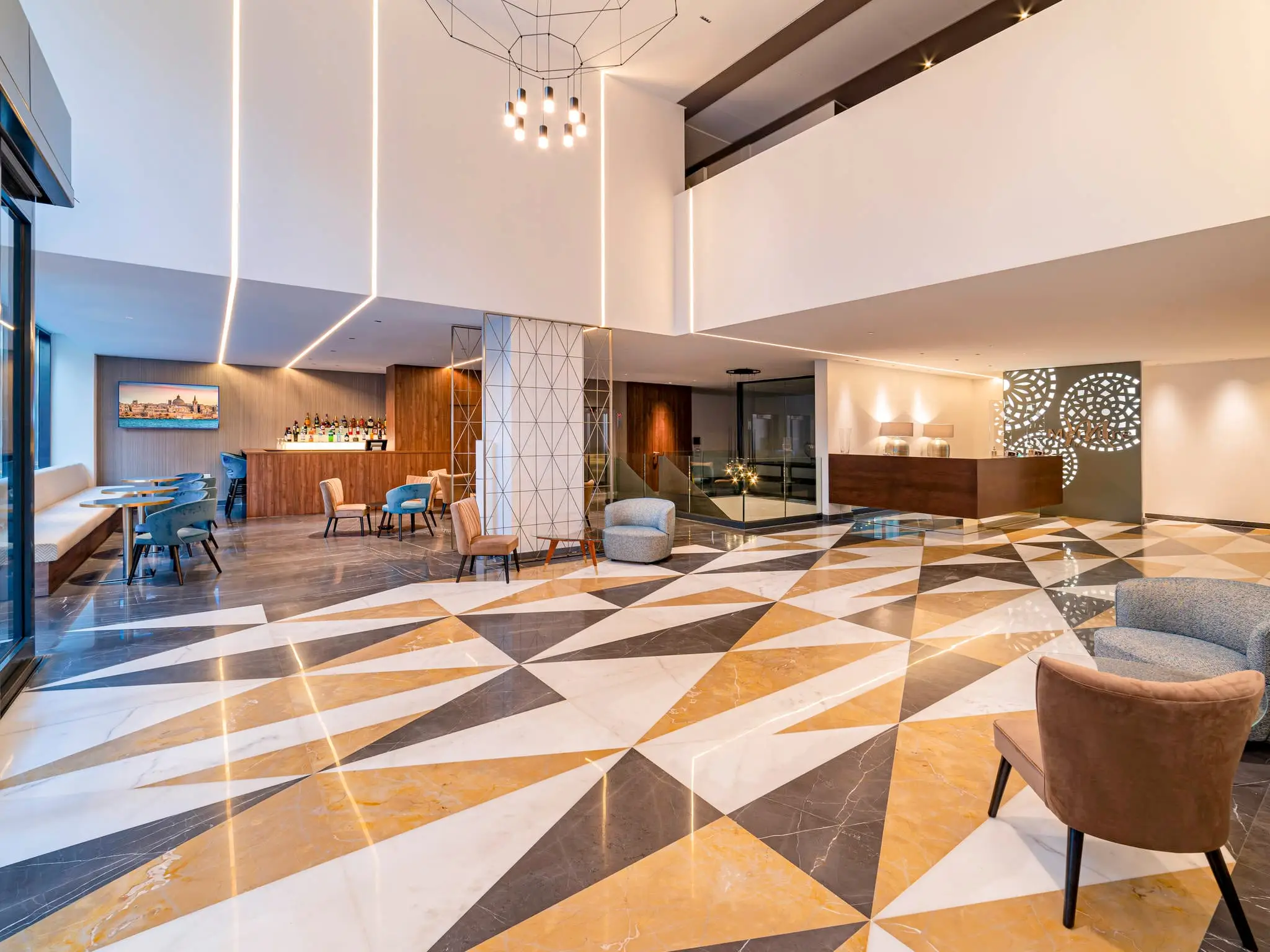 The double-height lobby and bar at the Mercure St Julian’s, with a patterned marble floor