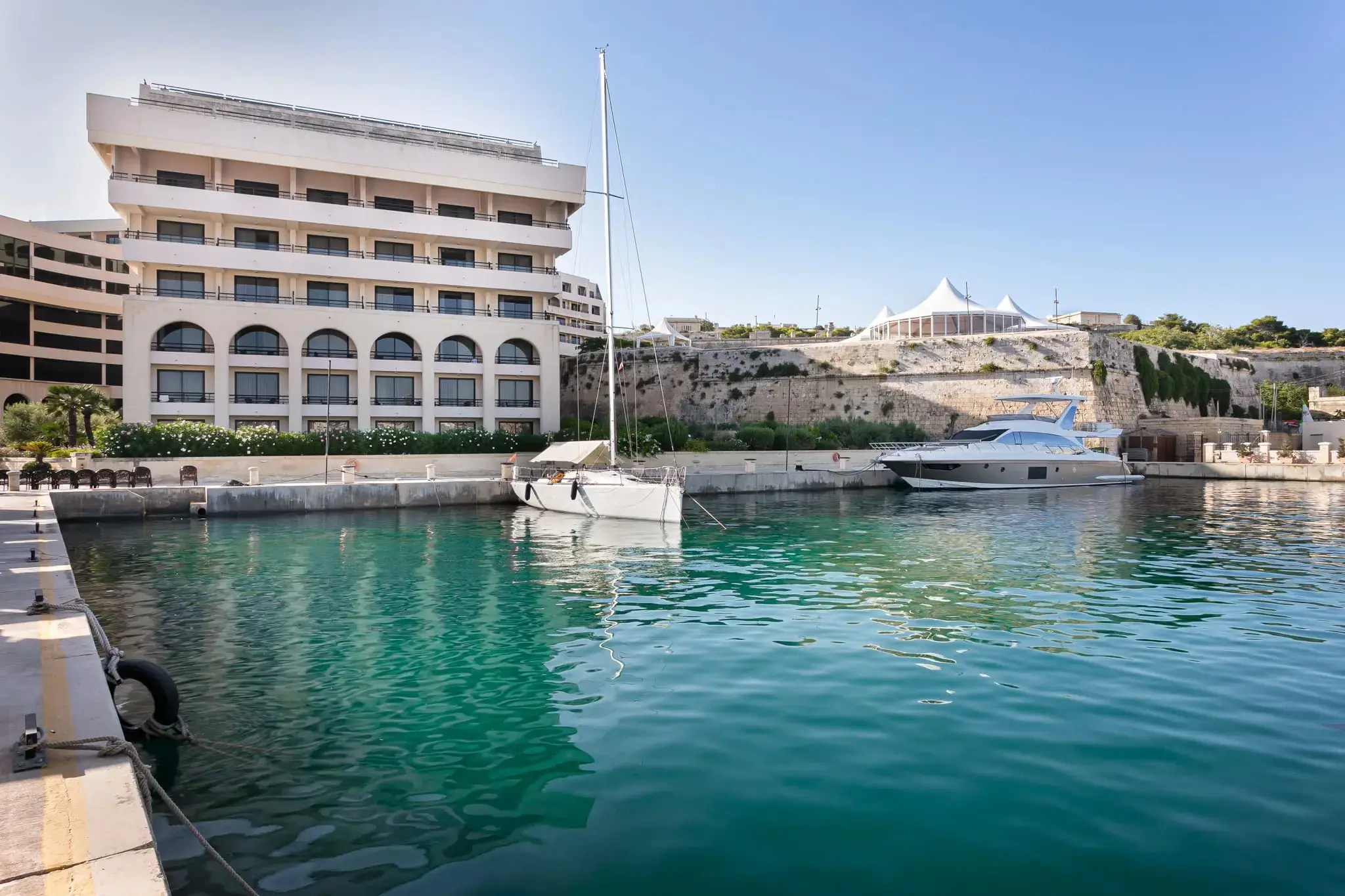 The hotel above its private marina below the Floriana bastions, with yachts moored at the quay