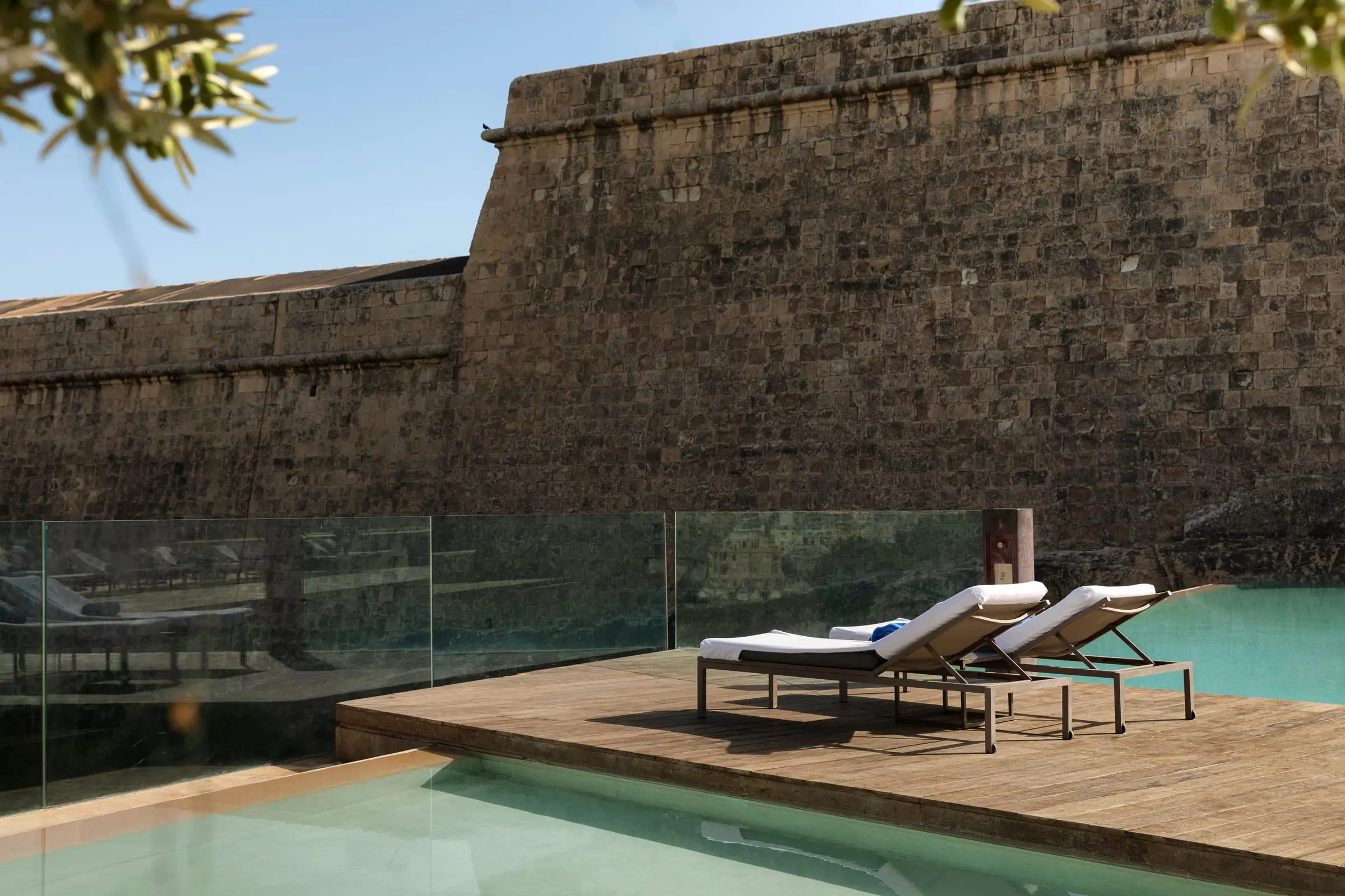 Sun loungers on the deck of the Bastion pool beneath the old fortification wall