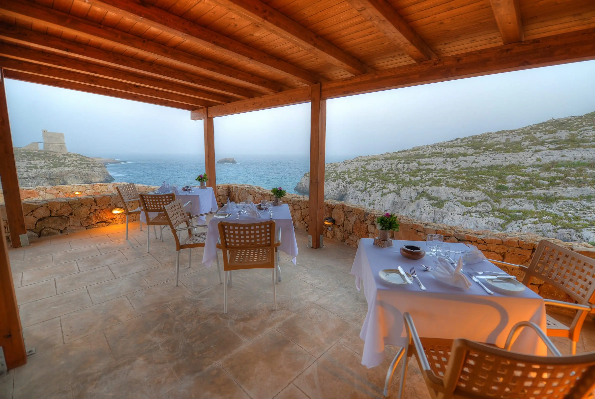 A covered terrace laid for dinner, the coast beyond