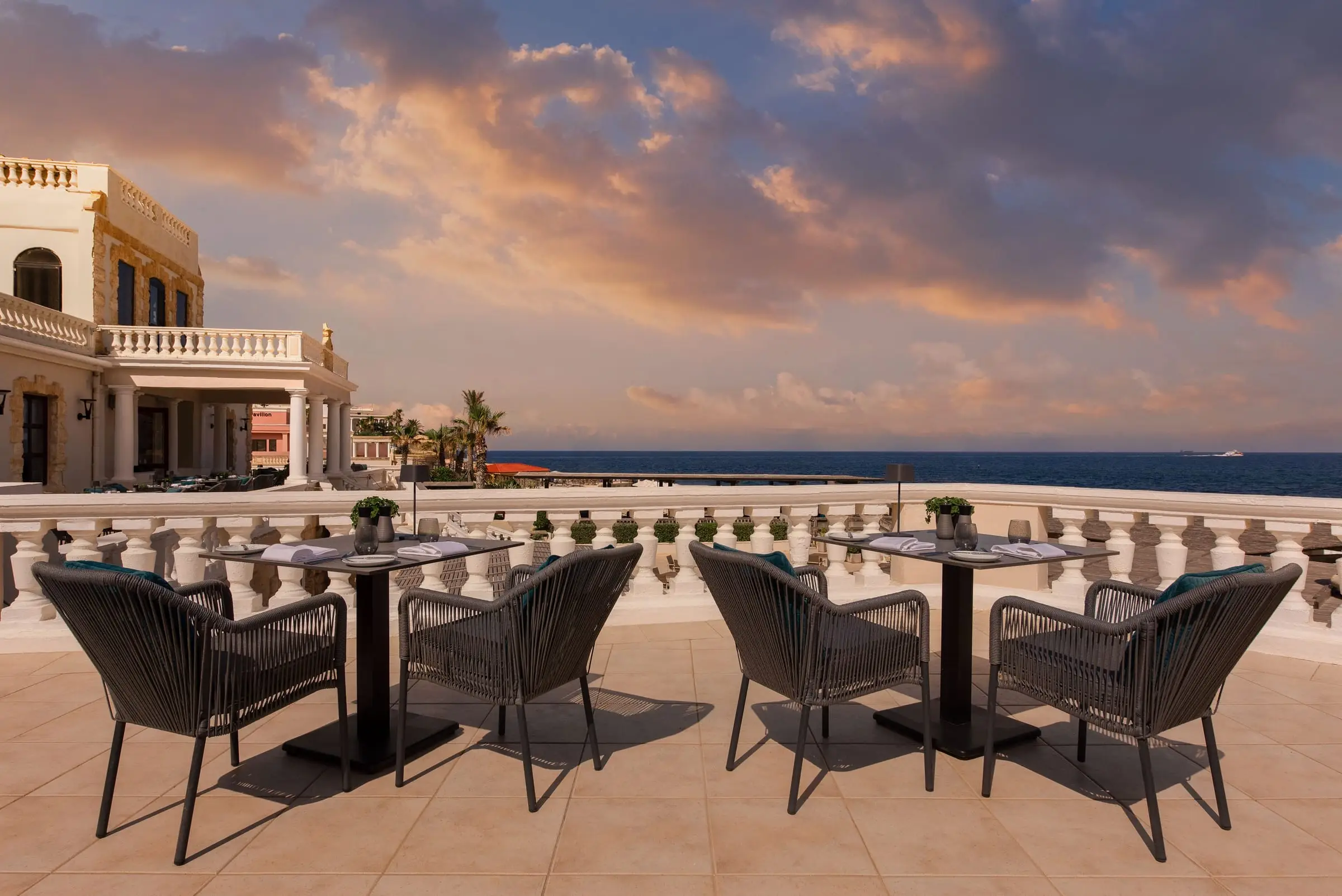 Tables on the Quadro restaurant terrace above the sea at sunset