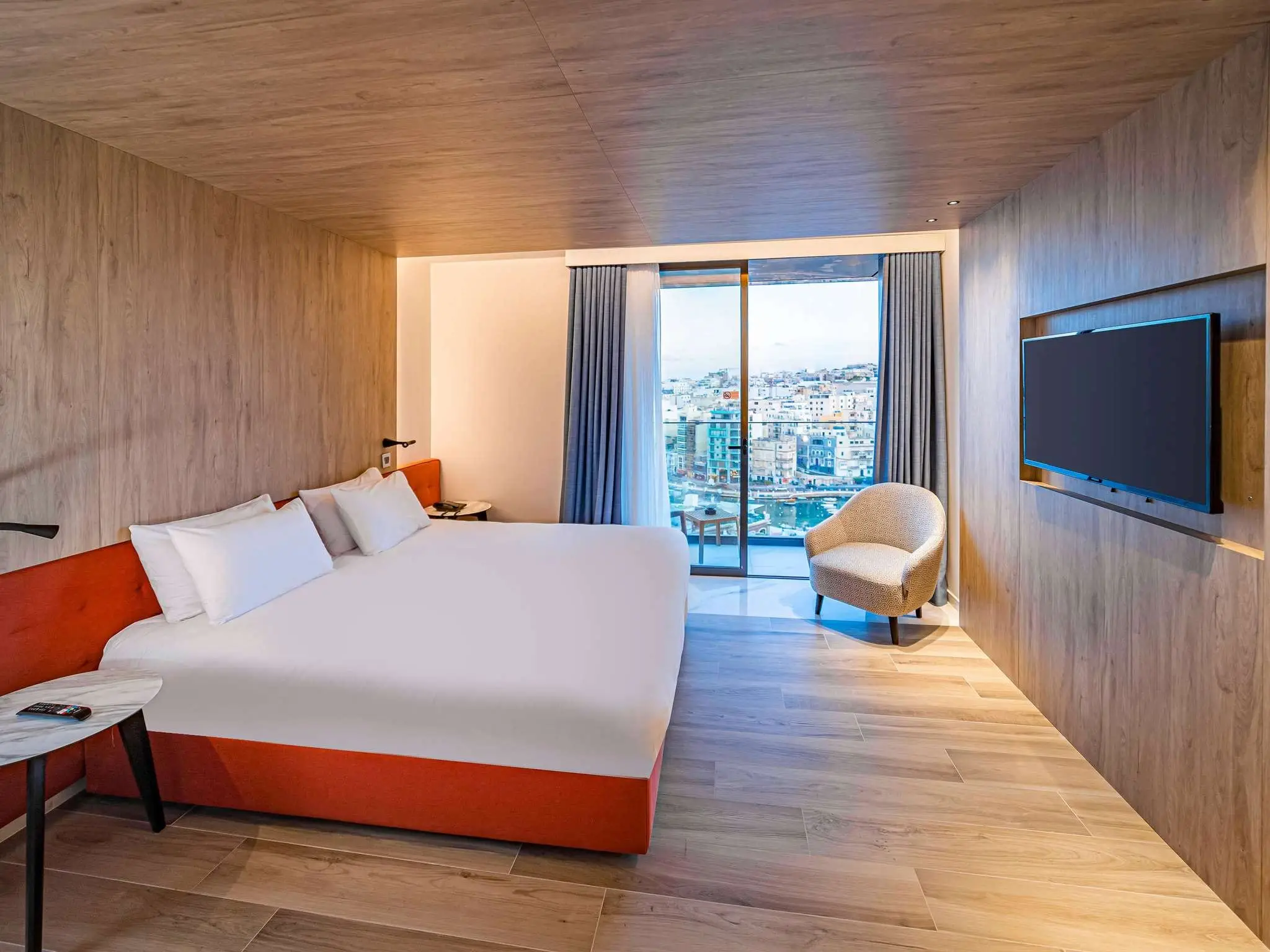 A room at the Mercure St Julian’s with timber-clad walls and a balcony