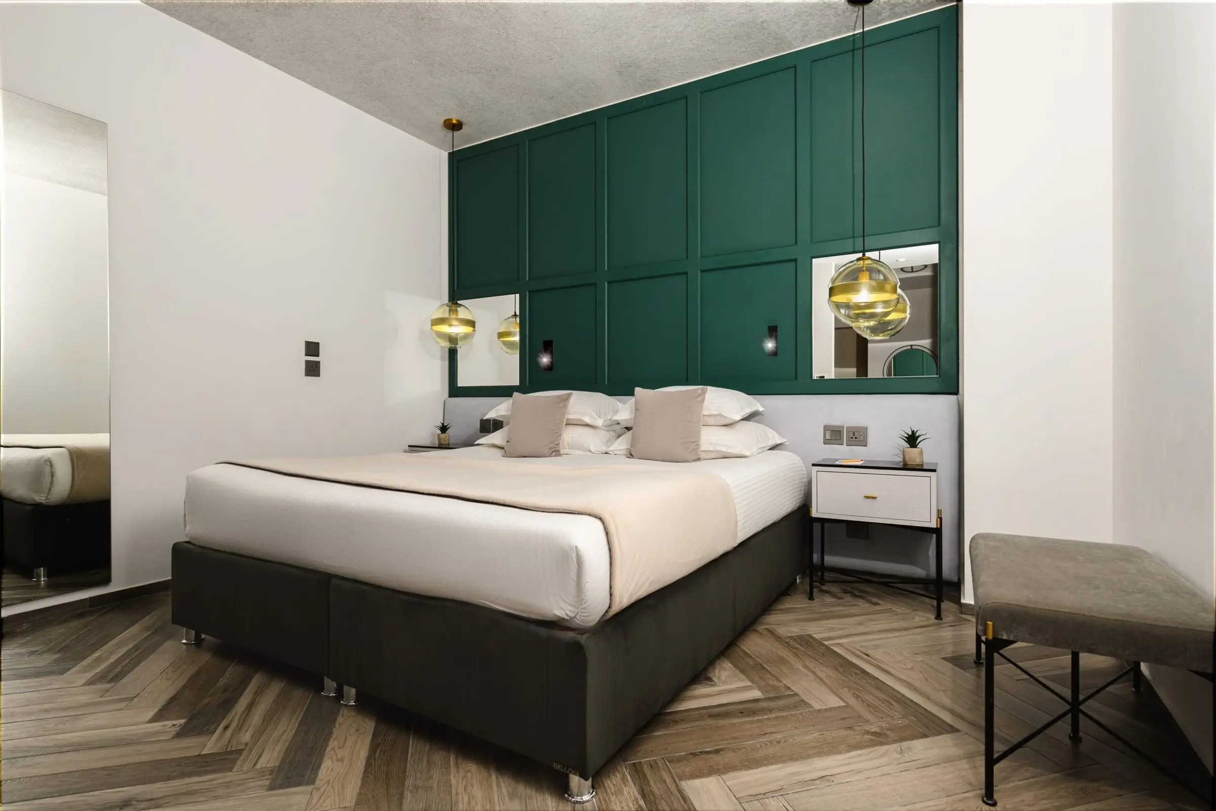 A guest room with a green panelled wall behind the bed
