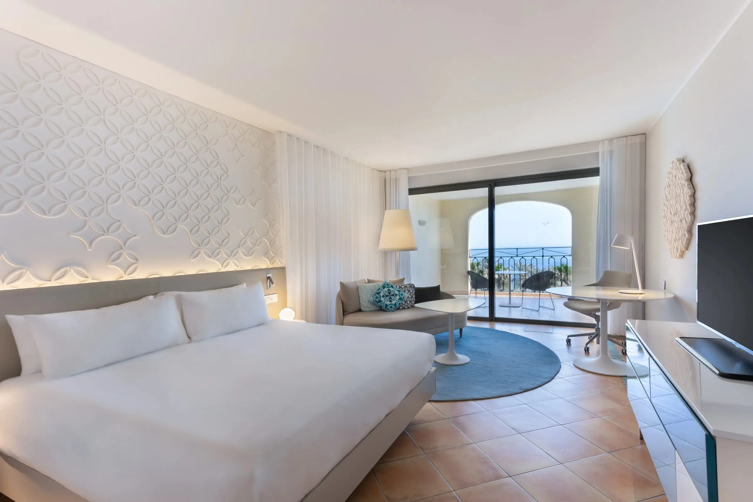 A king room with a sofa, a desk and a balcony facing the sea