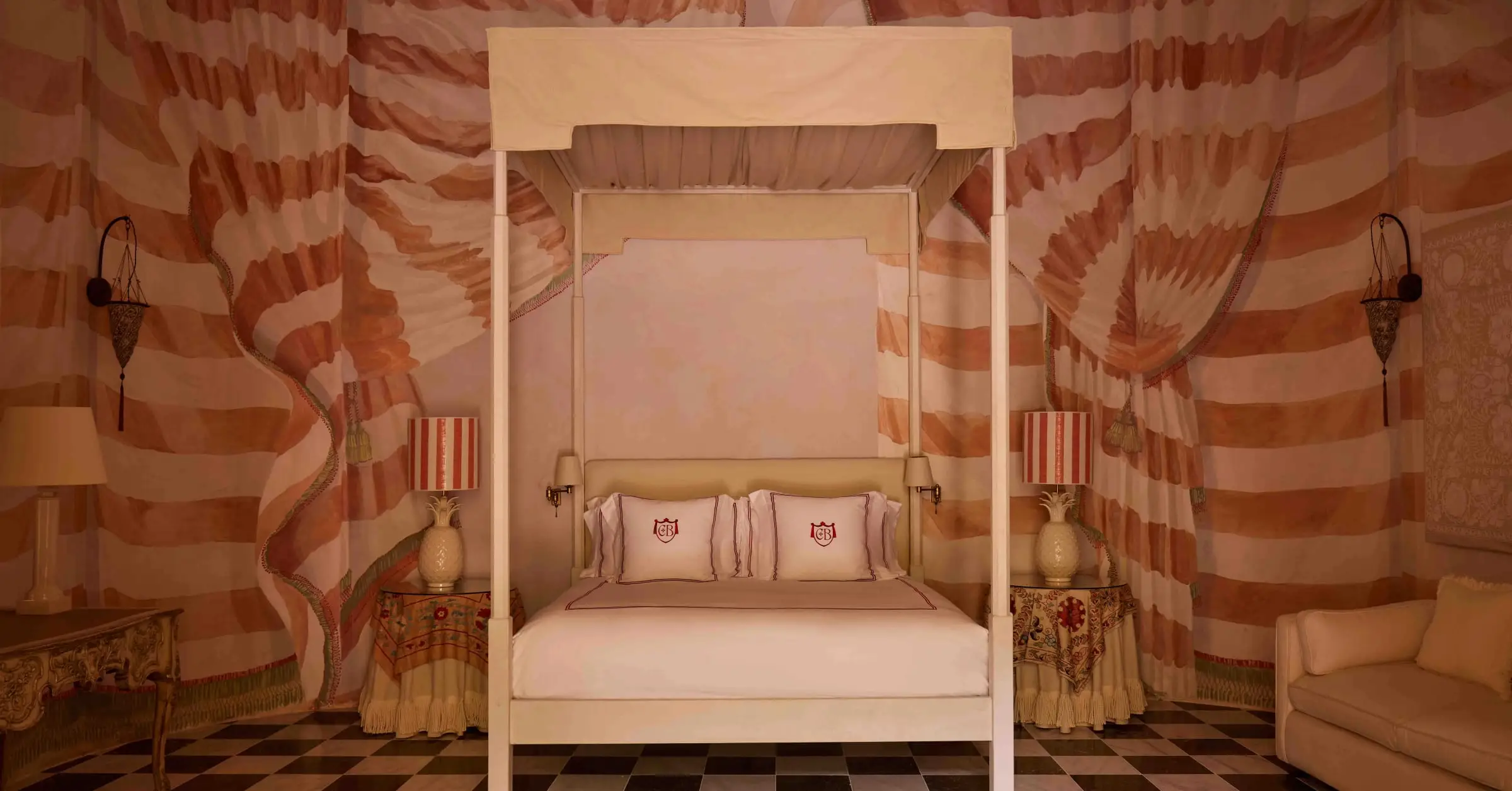 A guest room with a canopy bed and striped drapes