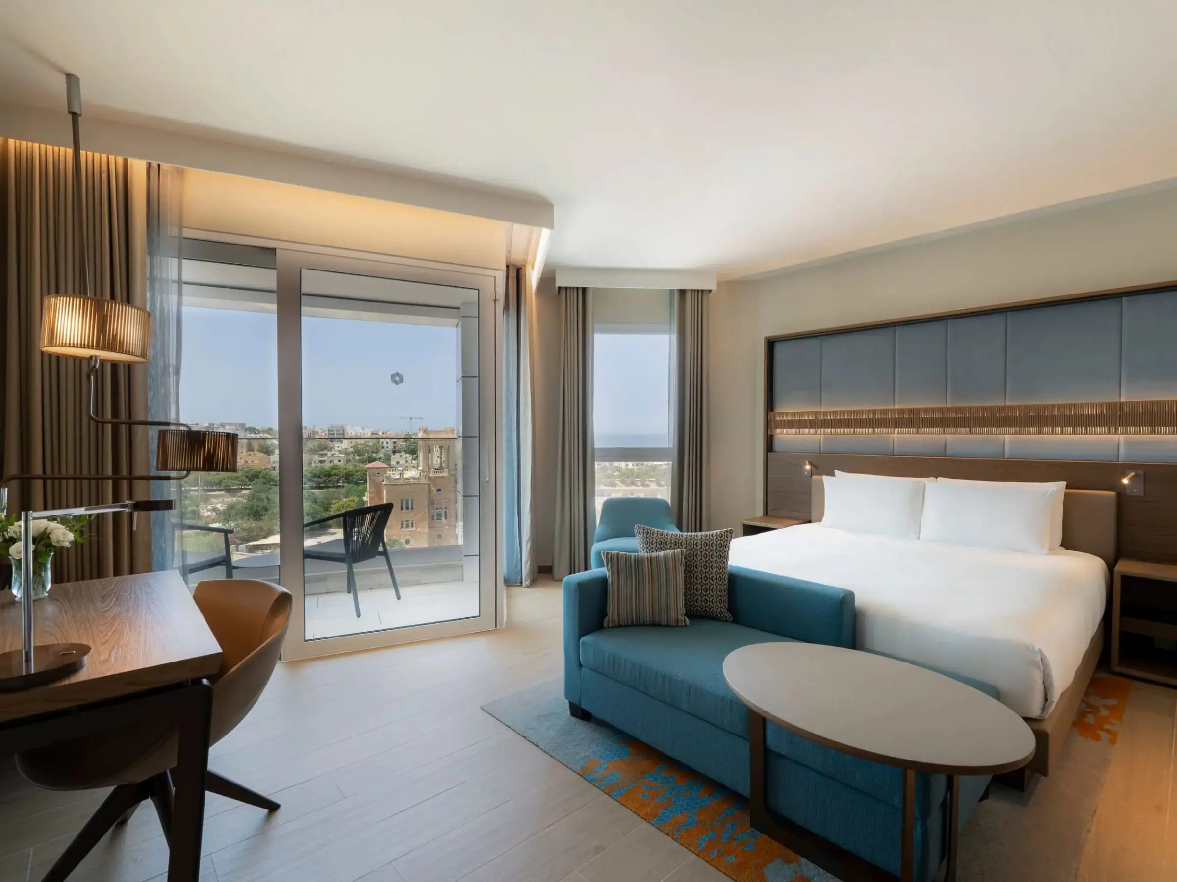 A junior suite with a king bed, a sofa and a balcony over St Julian's