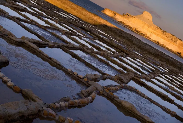 The salt pans at Xwejni in the evening light, the cliffs beyond