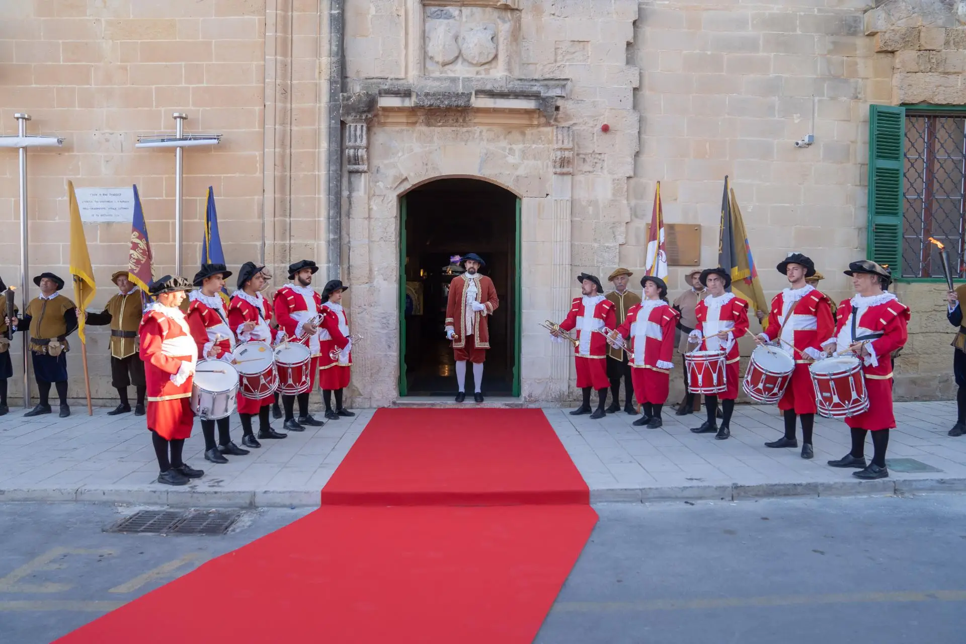 A costumed guard of honour with drums lining a red carpet at a palace entrance