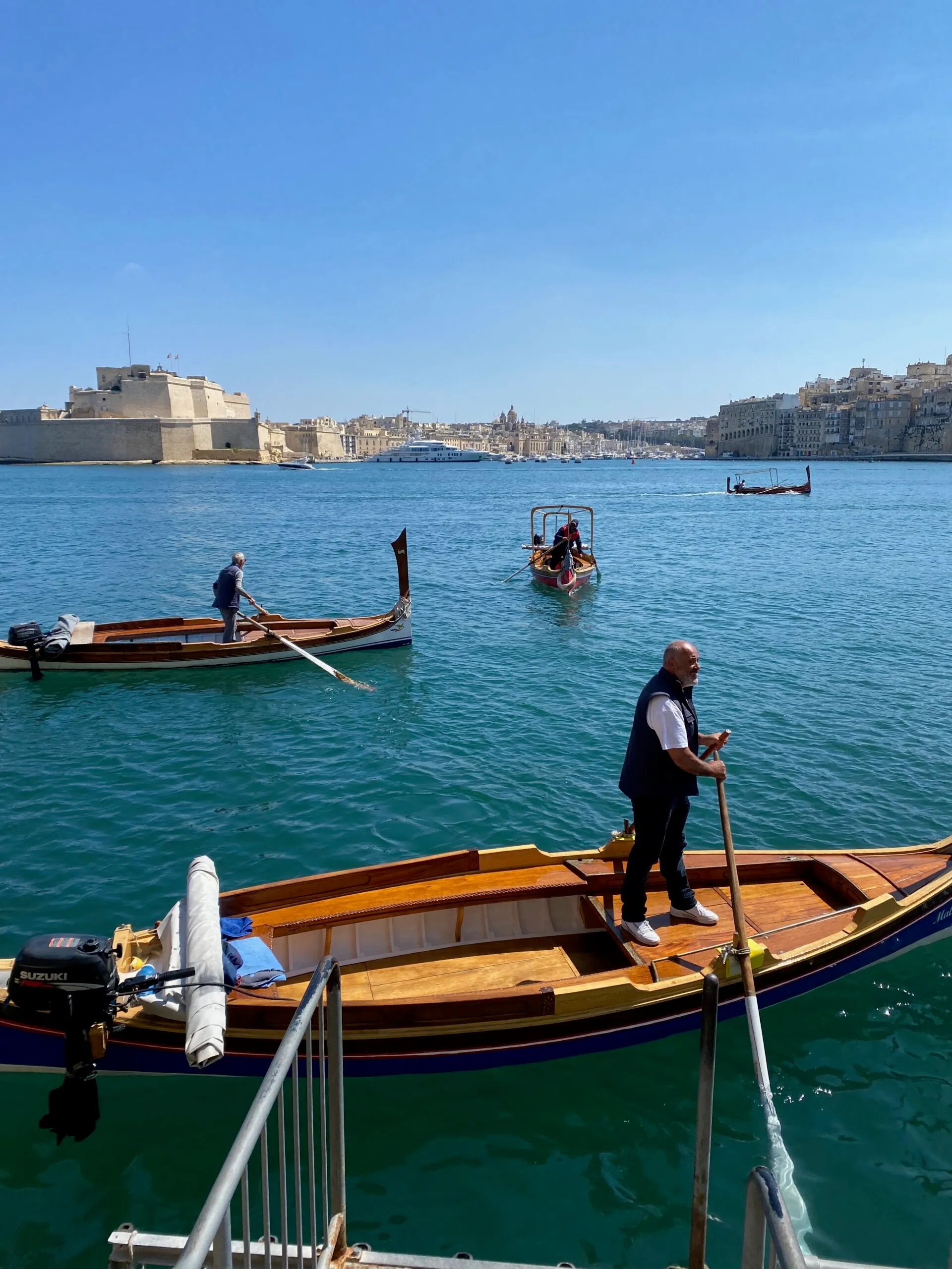 A traditional dgħajsa rowed across the harbour below Fort St Angelo, Birgu