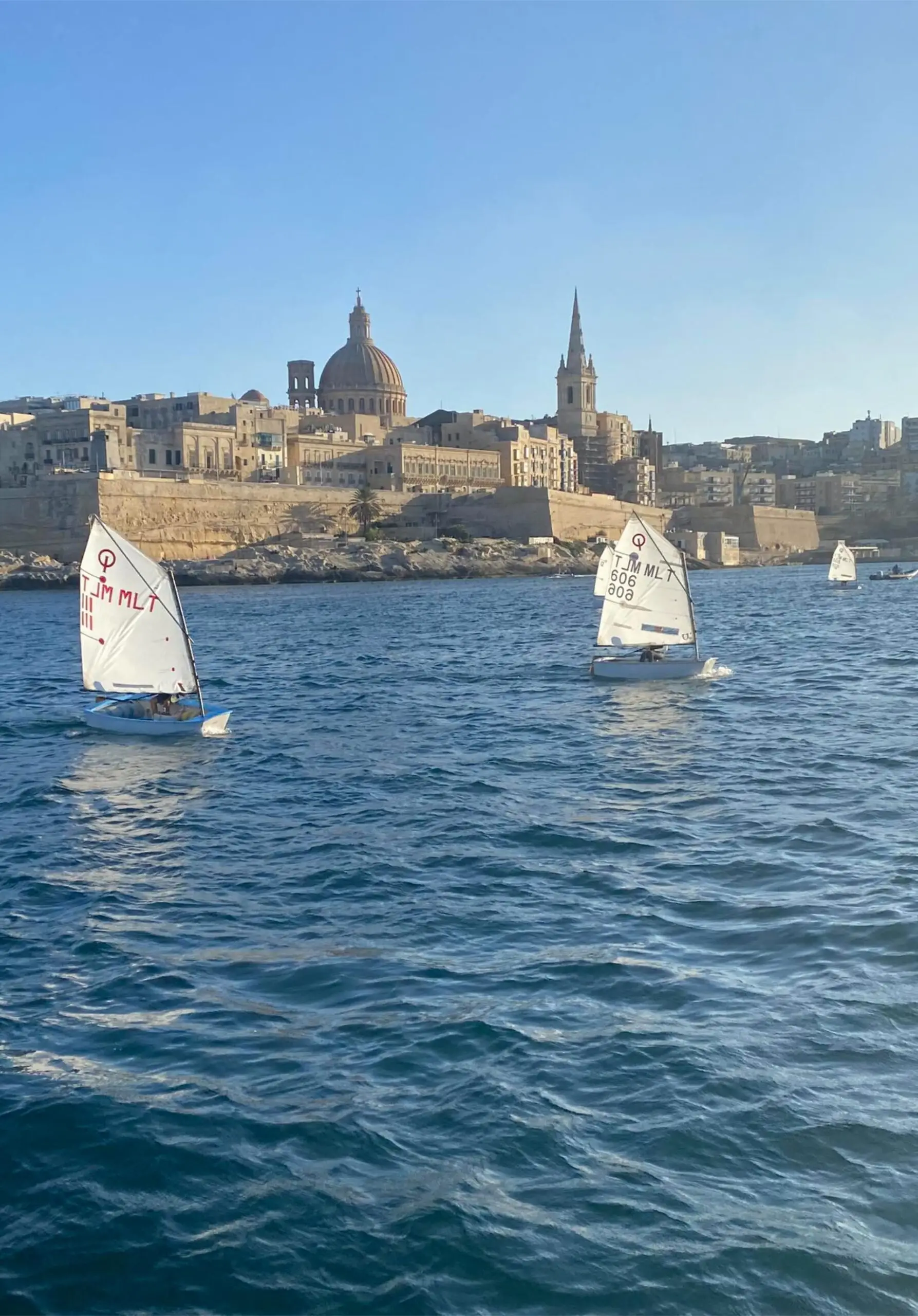 Sailing dinghies on the water with the Valletta skyline behind