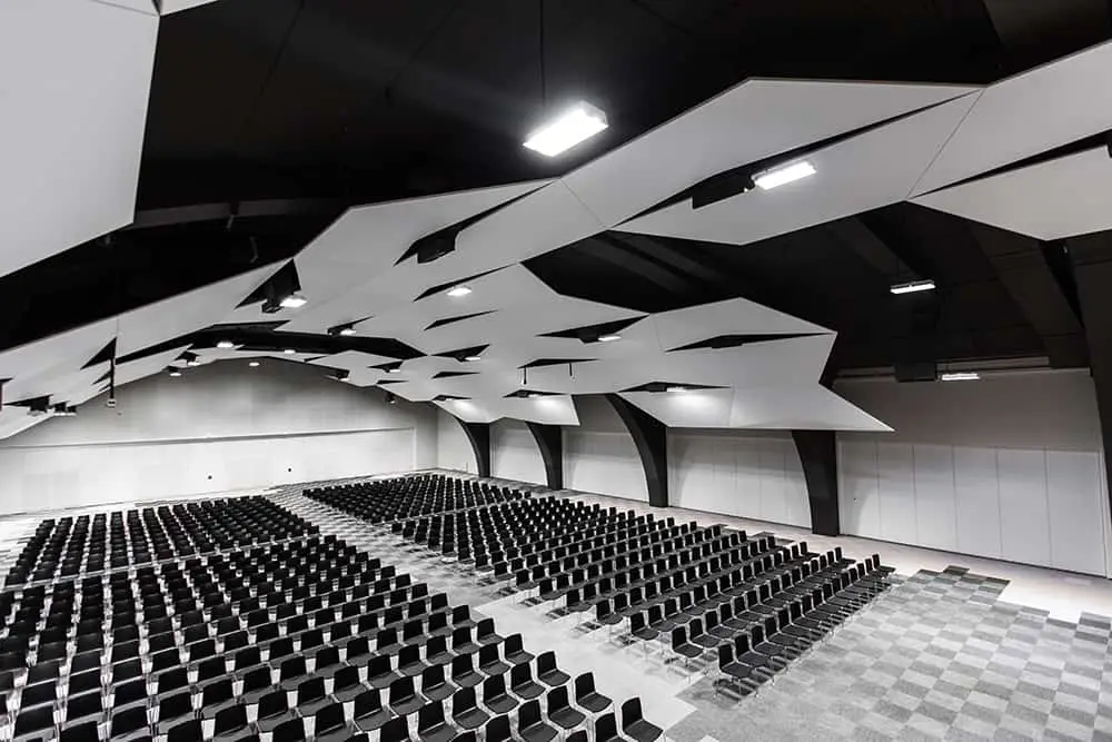 The arena set theatre style beneath its angular white ceiling panels