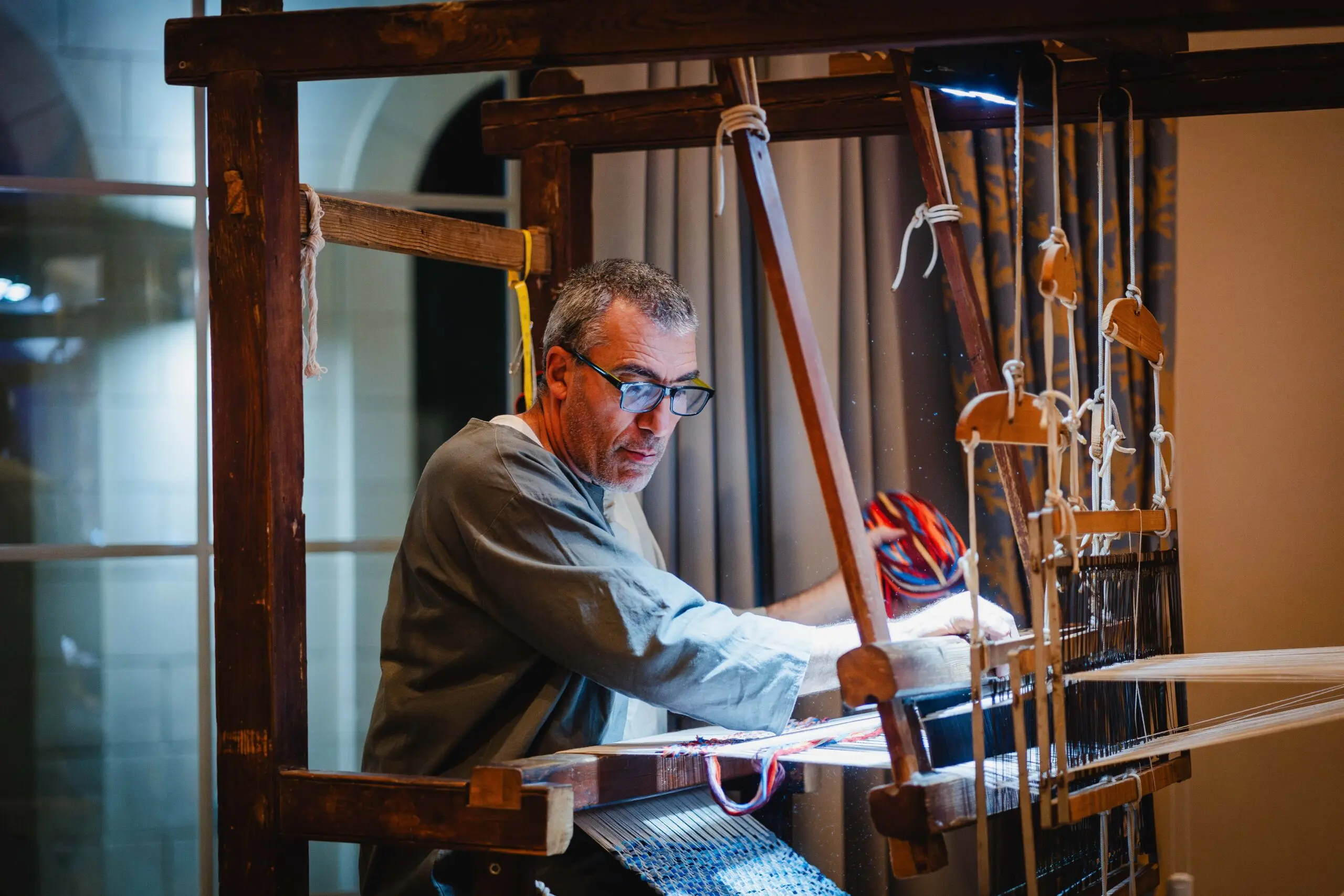 A weaver working a traditional wooden loom, threads running across the frame