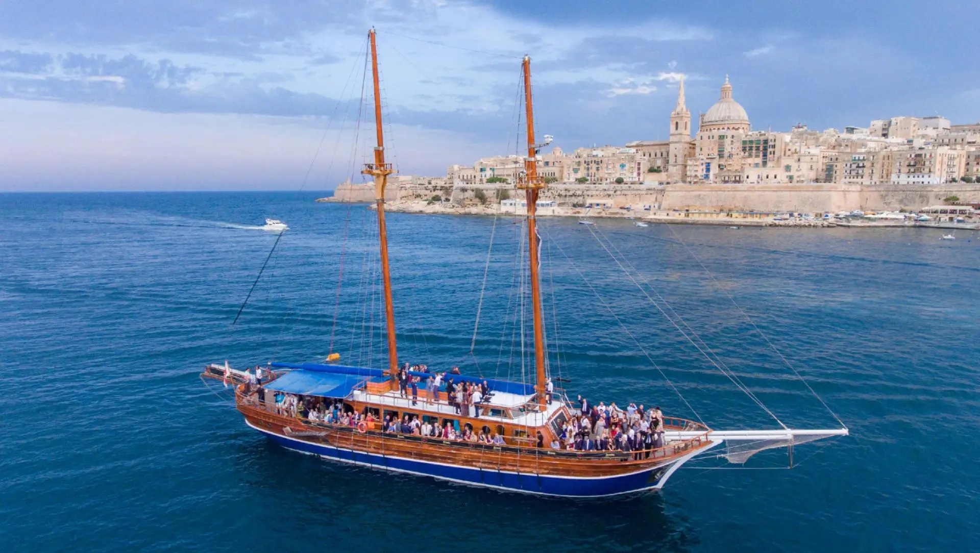 A two-masted schooner full of guests sailing past Valletta