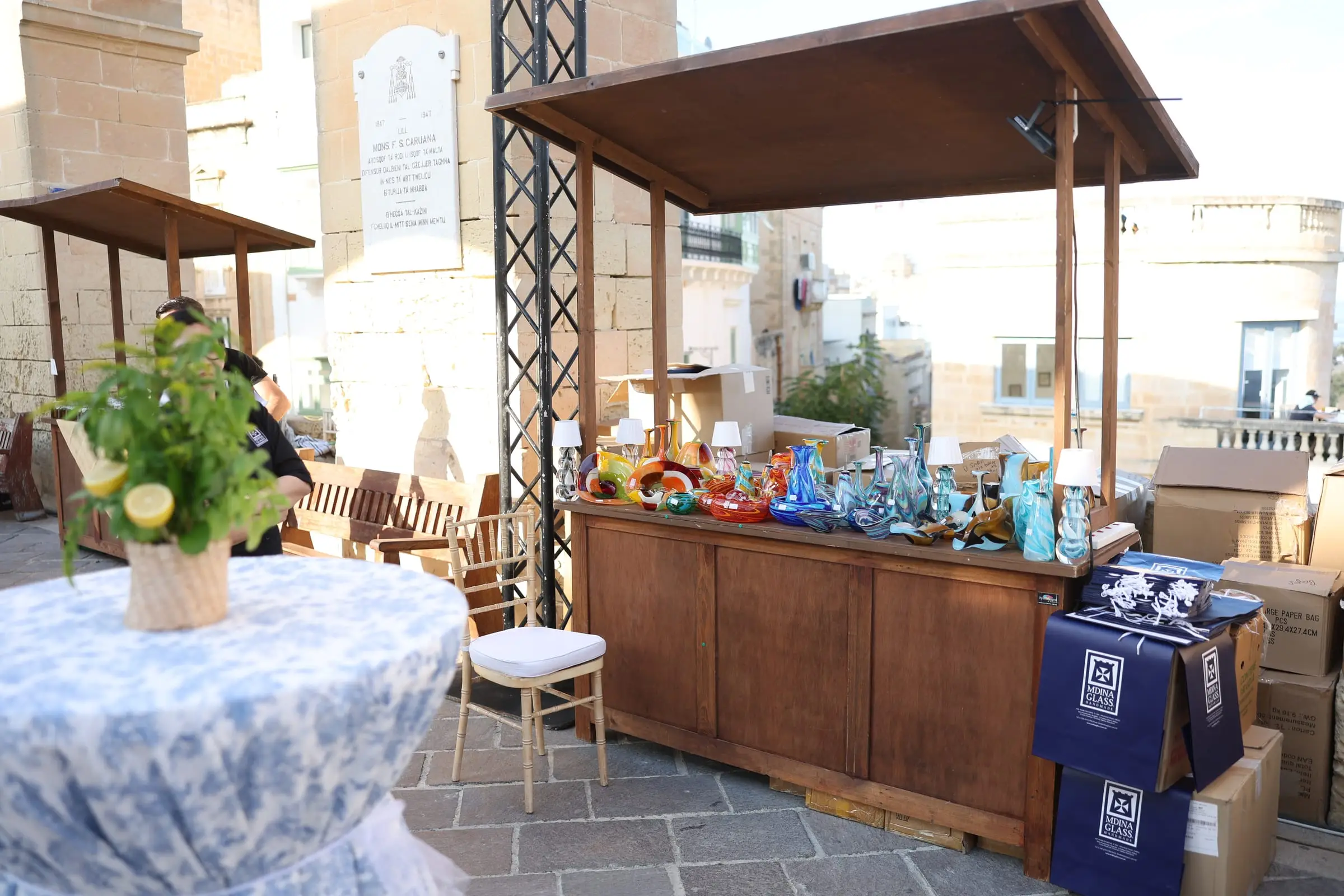 A timber market stall of hand-blown Maltese glass set up under the Barrakka arches