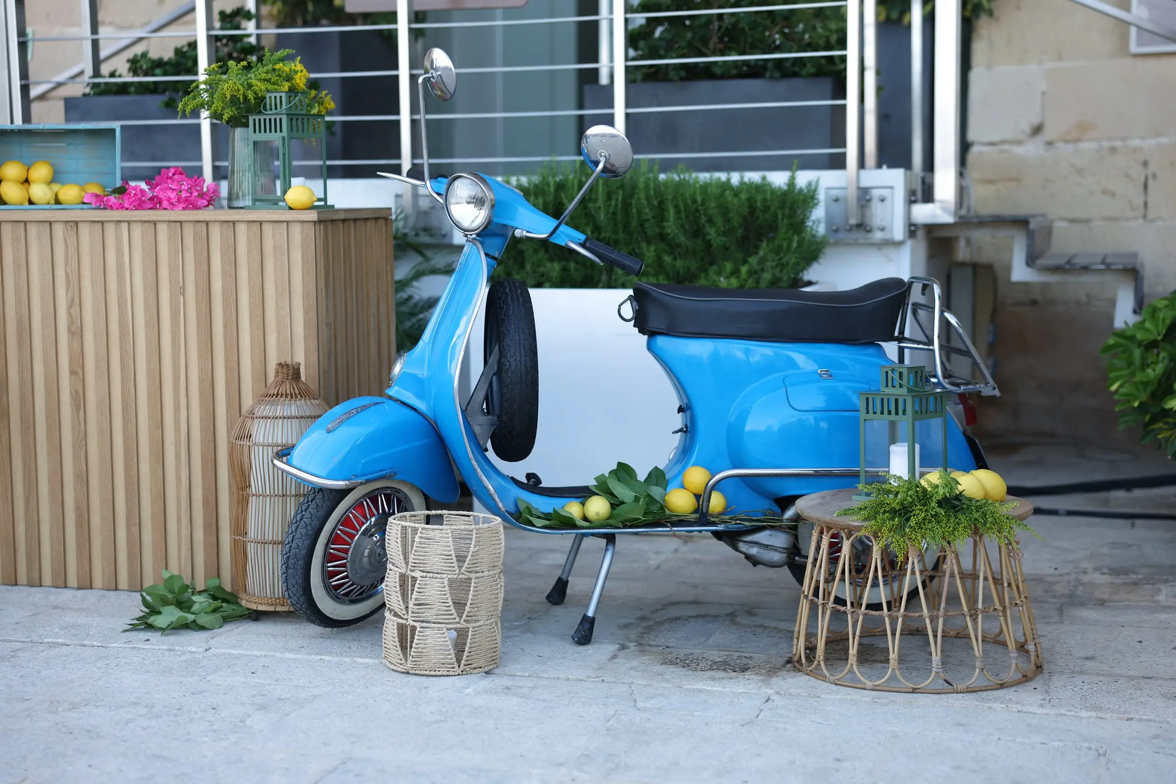 A vintage blue Vespa dressed with lemons beside a timber aperitivo bar on the bastions