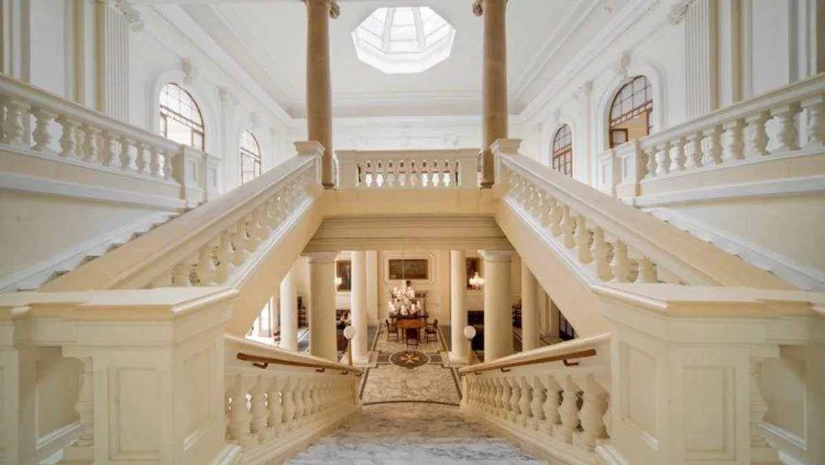 A white marble double staircase rising under a skylight