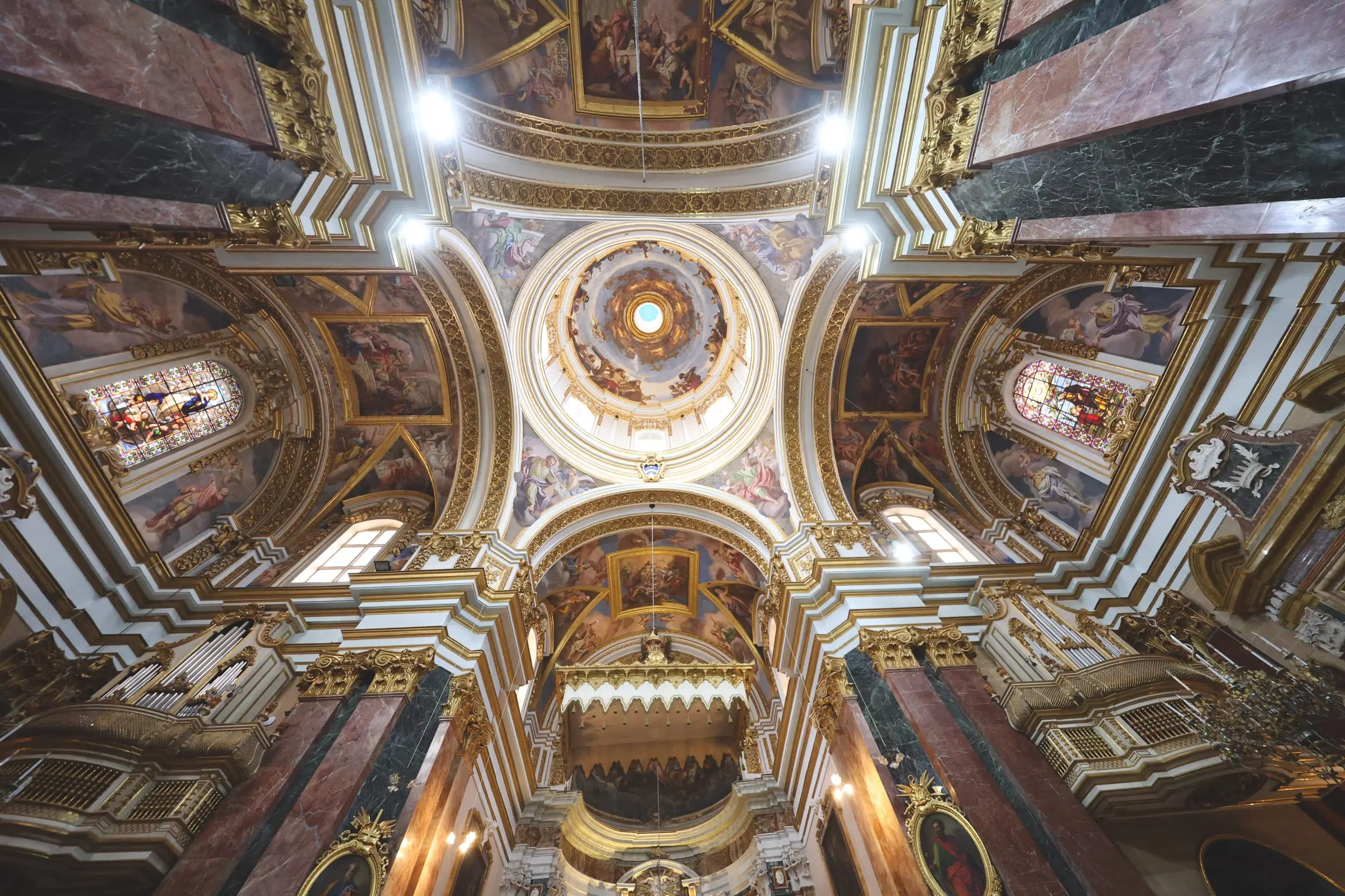 Looking straight up into the dome of St Paul's Cathedral: painted vaults, gilded mouldings and red marble piers