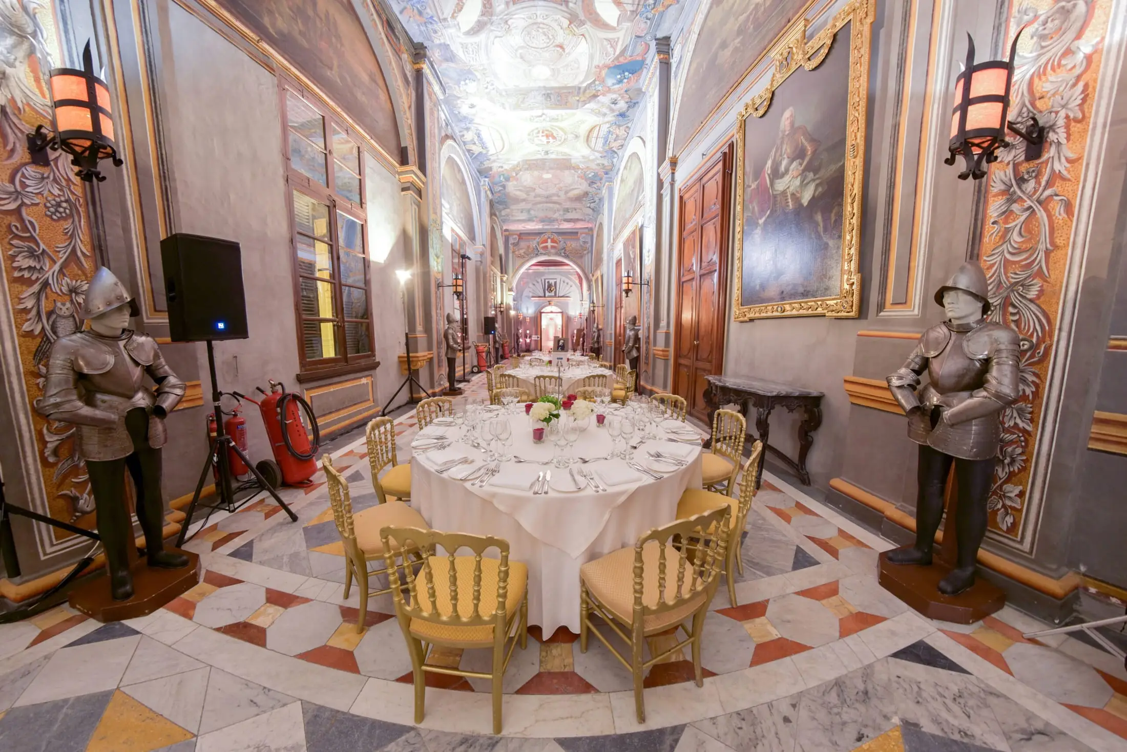 A round table set for dinner in a state room of the Grandmaster’s Palace, flanked by suits of armour