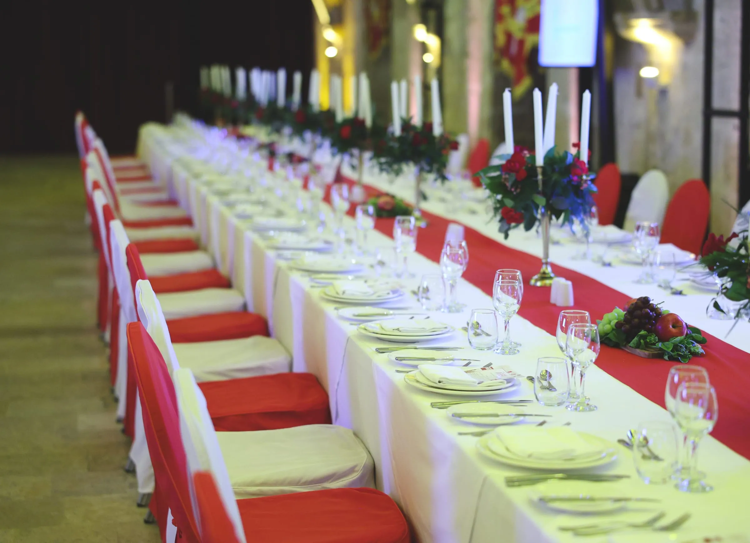 A long imperial table in white and red, candelabras and roses running into the distance
