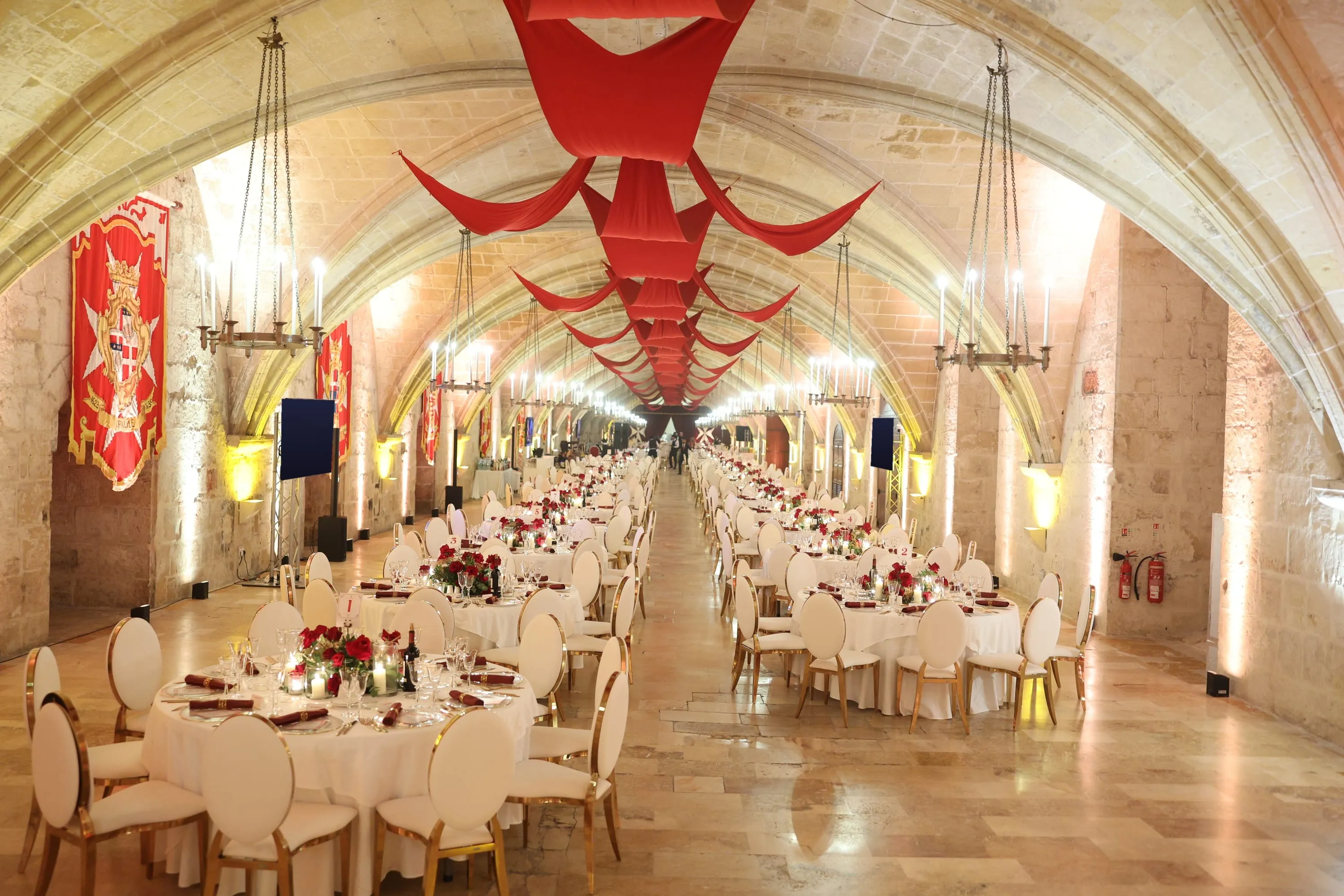 La Valette Hall in the Sacra Infermeria laid for dinner under candle chandeliers and red drapes