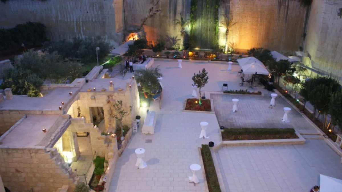 A quarry floor lit for an evening reception, cocktail tables among the stone walls
