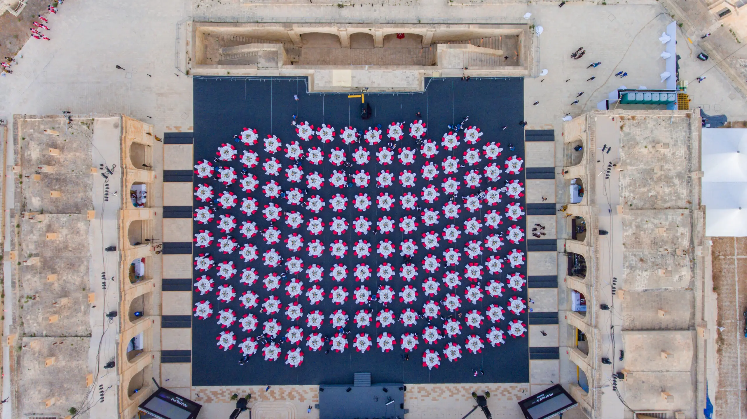 A gala dinner build seen from directly above: more than a hundred round tables laid out inside a fort courtyard