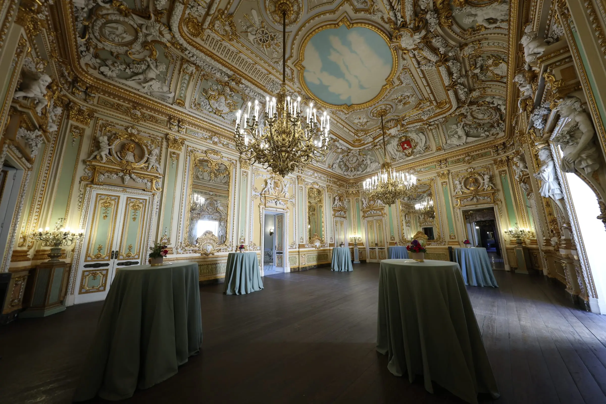 The gilded baroque ballroom of Palazzo Parisio set with cocktail tables before the welcome dinner