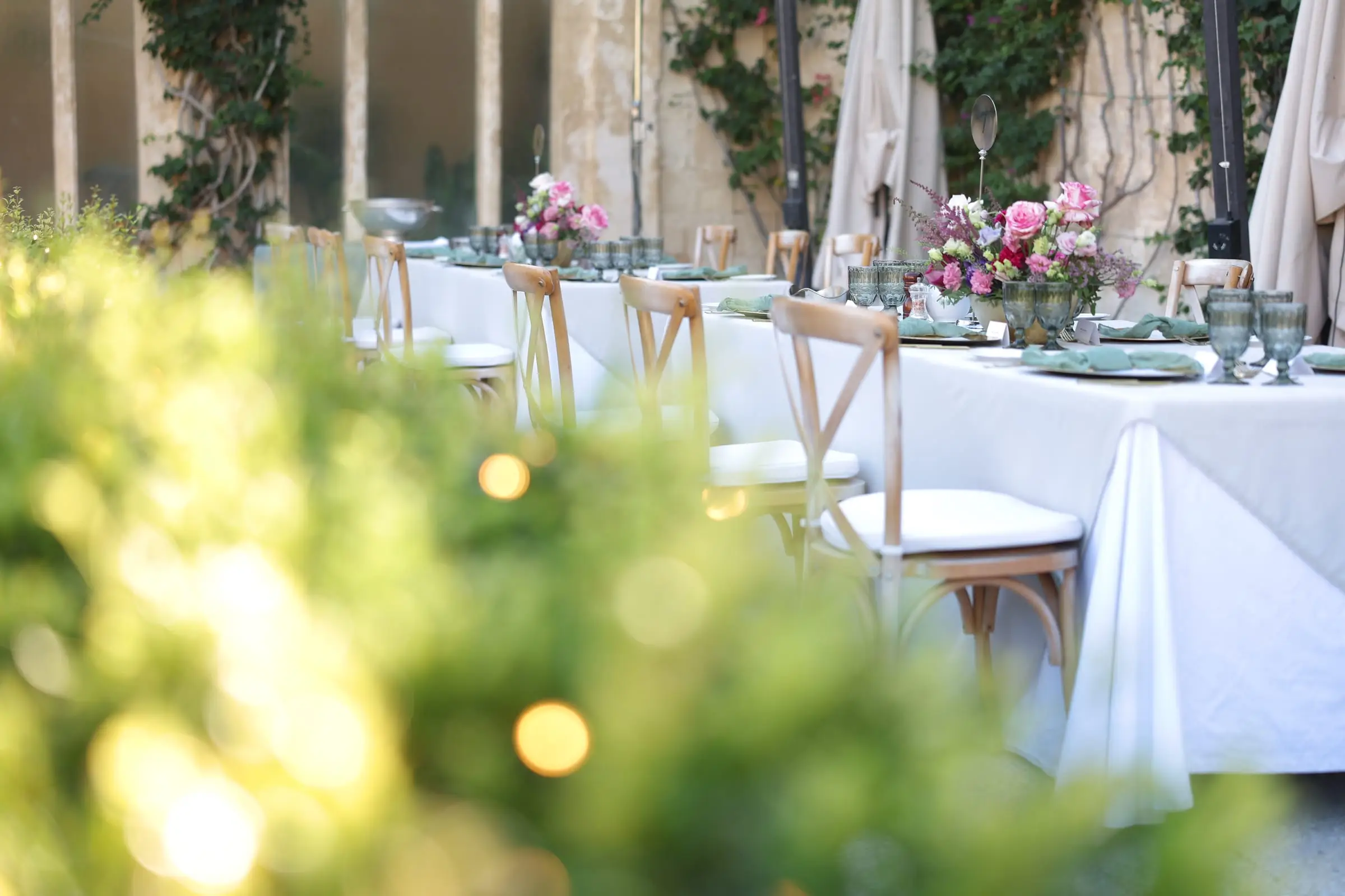 Long tables laid with glassware and pink roses in the walled garden of Palazzo Parisio