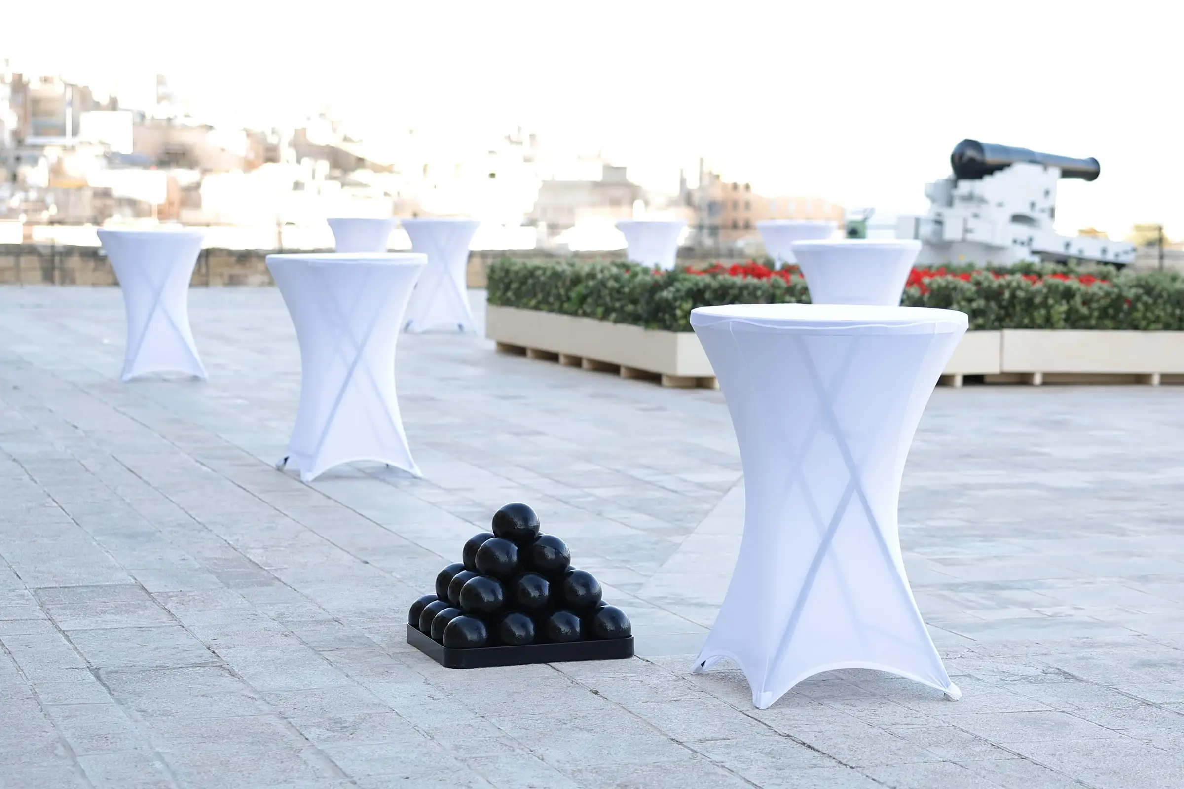 A pyramid of black cannonballs beside white-draped cocktail tables on the Saluting Battery