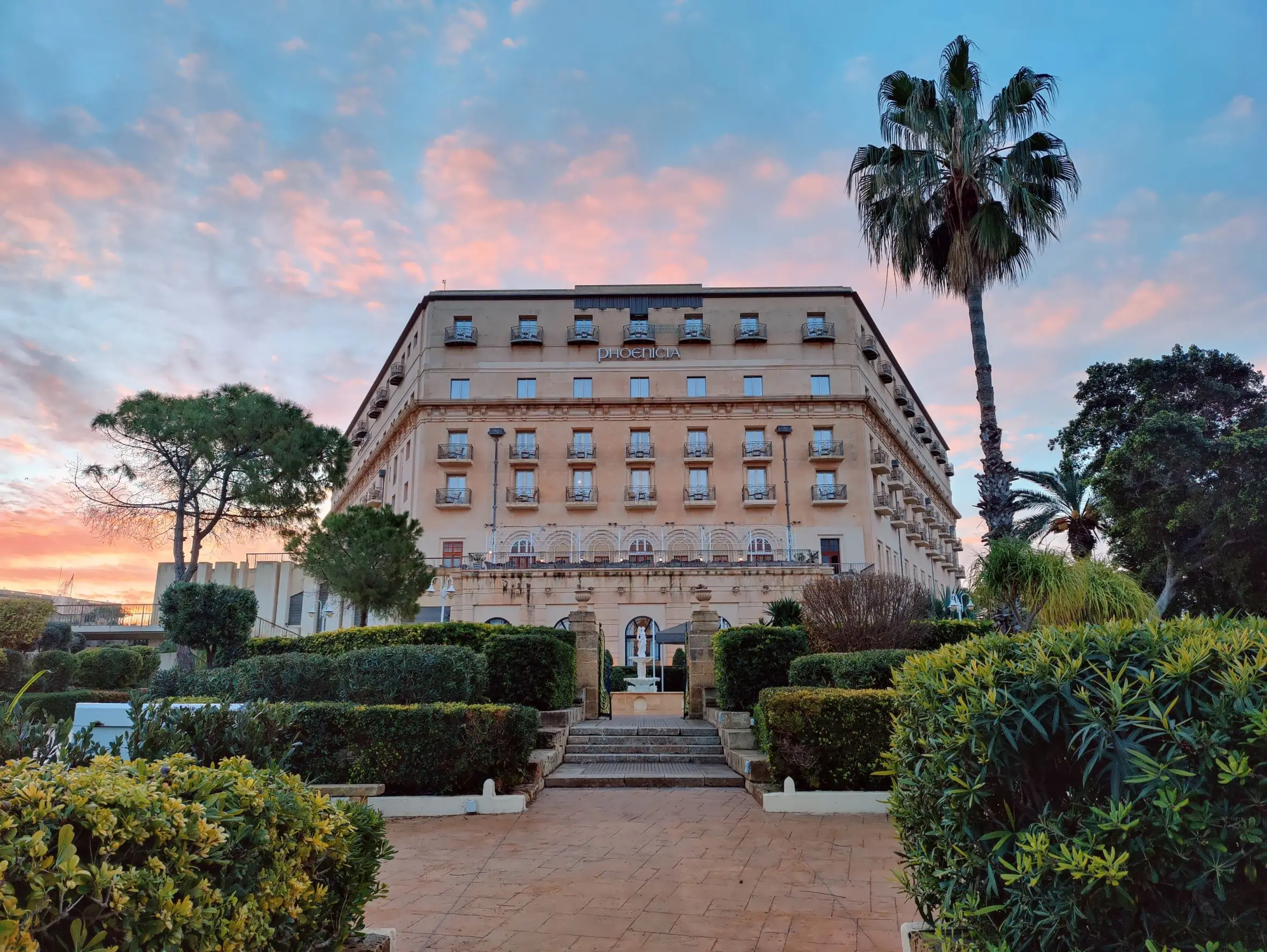 The Phoenicia hotel and its gardens under a pink evening sky