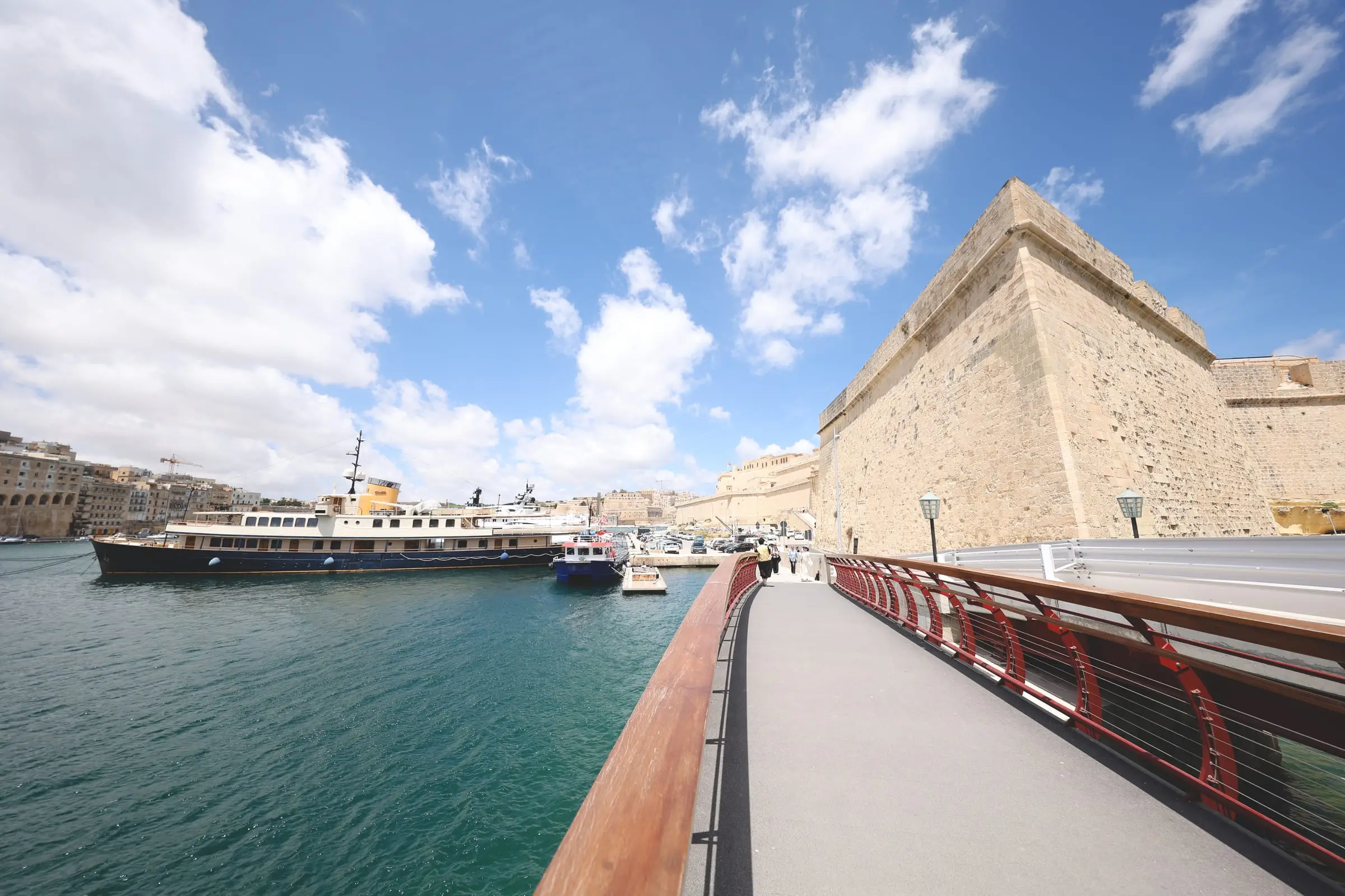 The footbridge to Fort St Angelo in Birgu, a classic motor yacht moored in the creek