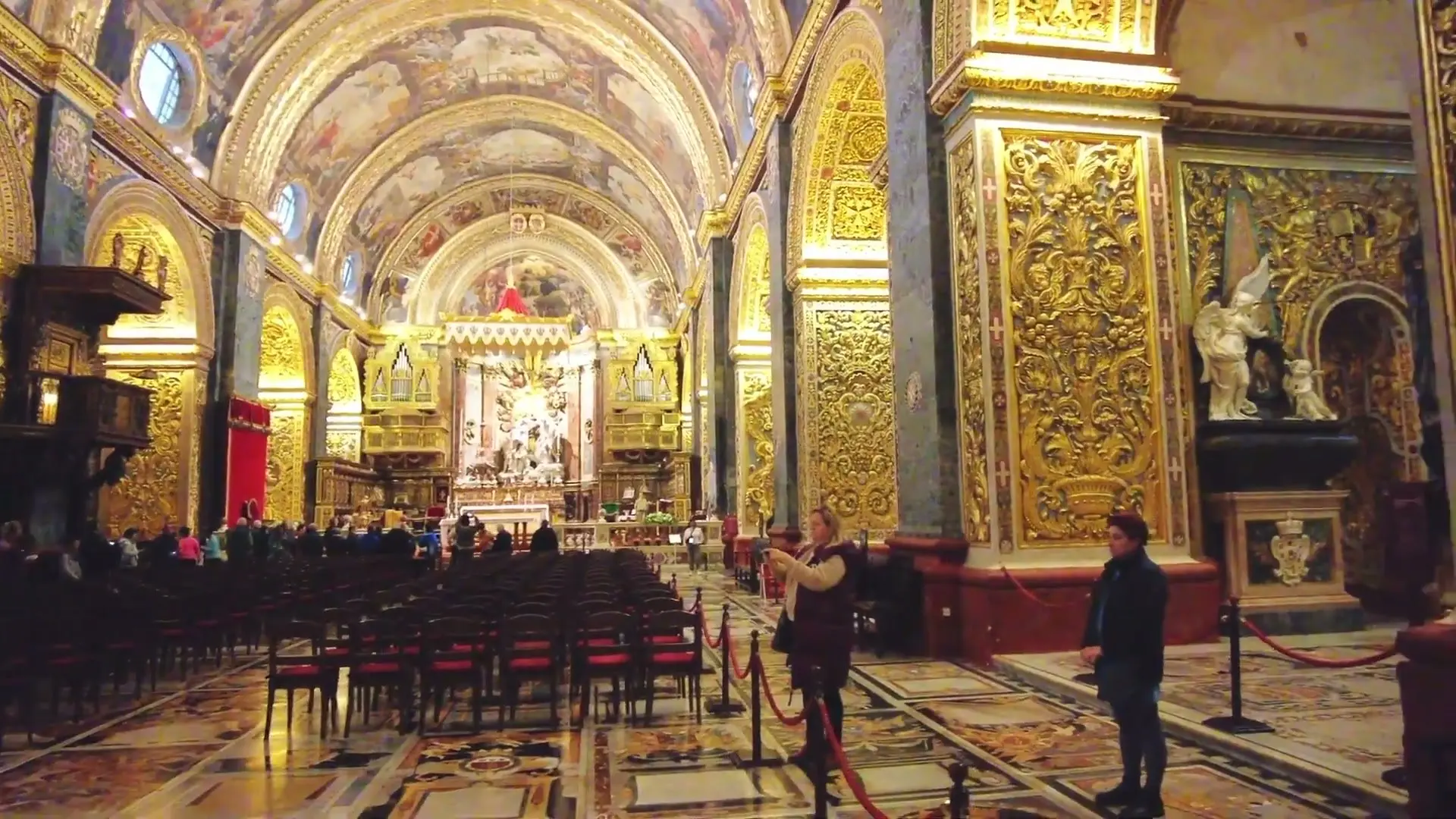The nave of St John's Co-Cathedral in Valletta, its walls carved and gilded and its vault painted
