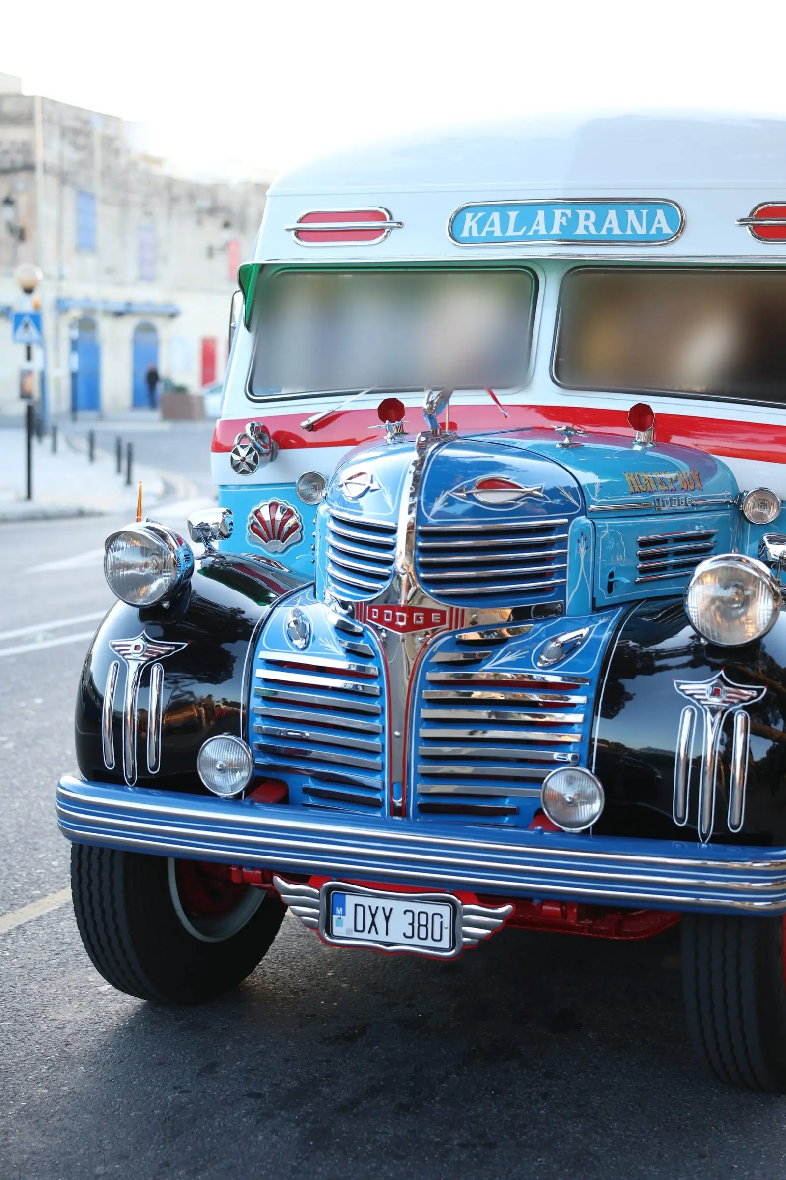 The front of a restored vintage Maltese bus in blue, cream and red, chrome grille and headlamps, a Kalafrana destination board above the windscreen
