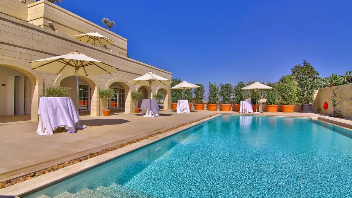 A pool terrace at Xara Lodge laid with cocktail tables and parasols